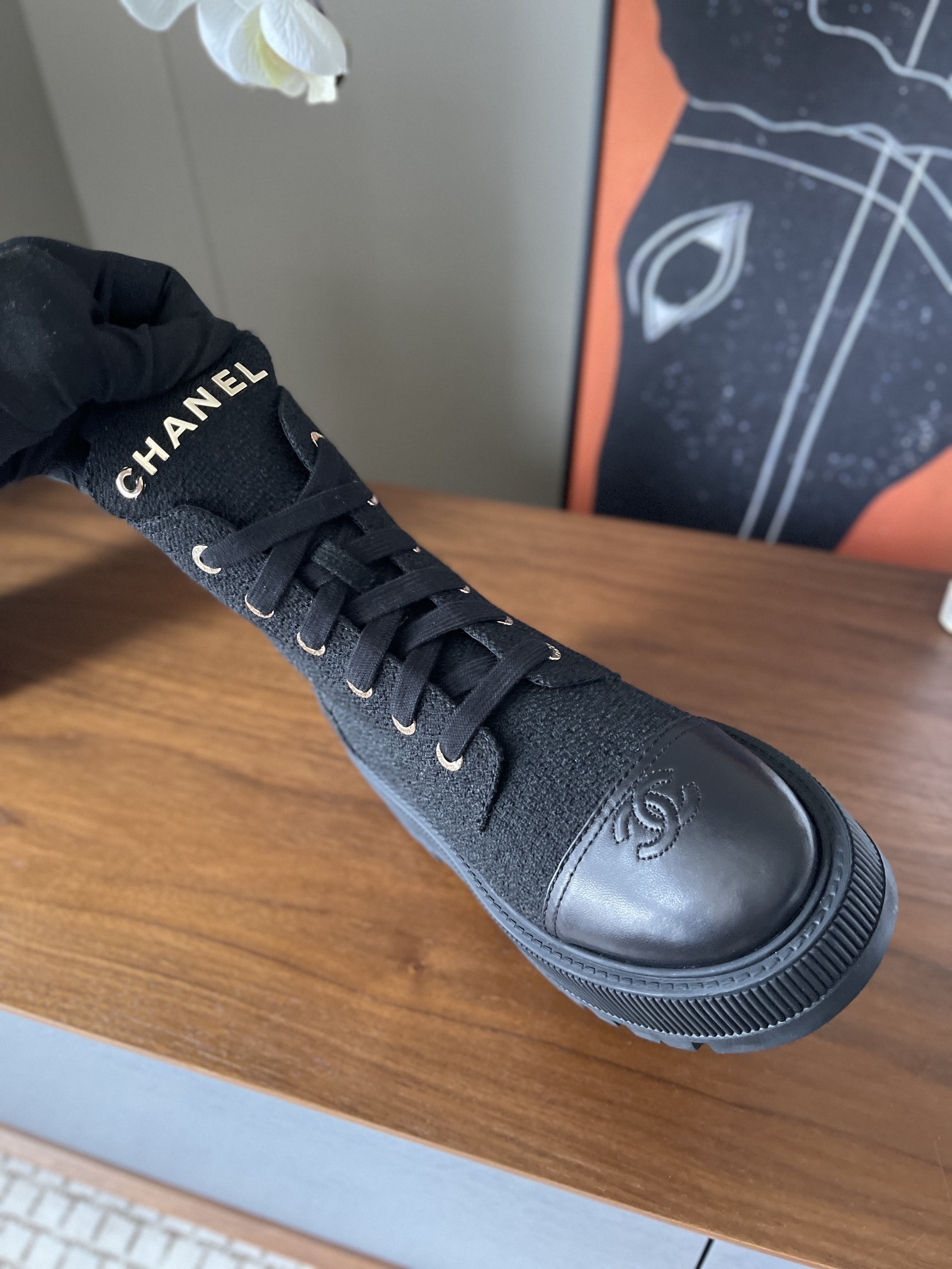 A pair of Chanel black tweed lace-up combat boots with gold lettering and chunky platform soles placed on a wooden surface. - Hình 5
