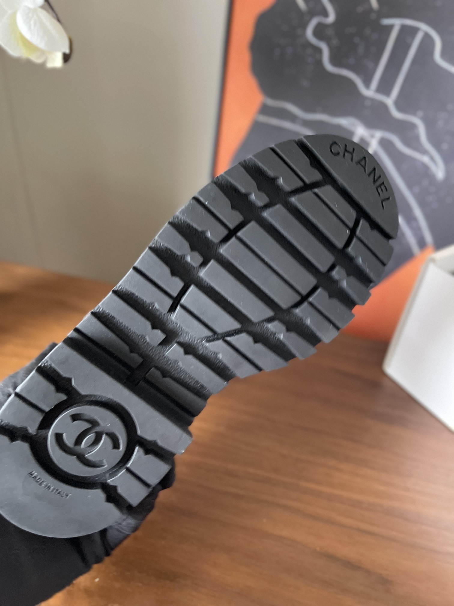 Pair of Chanel white tweed ankle boots with black leather toe caps and chunky black platform soles on a wooden surface. - Hình 9