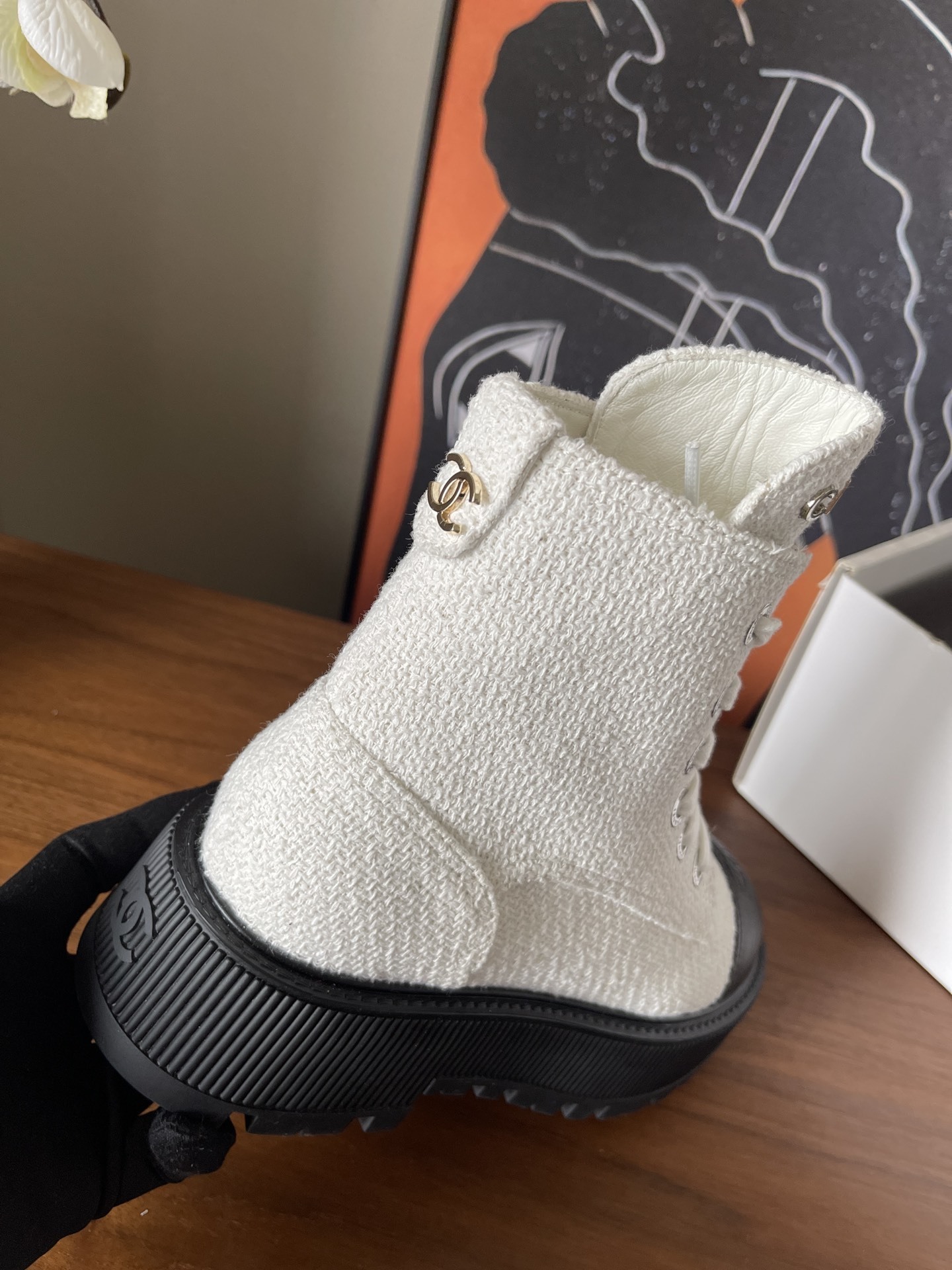 Pair of Chanel white tweed ankle boots with black leather toe caps and chunky black platform soles on a wooden surface. - Hình 7