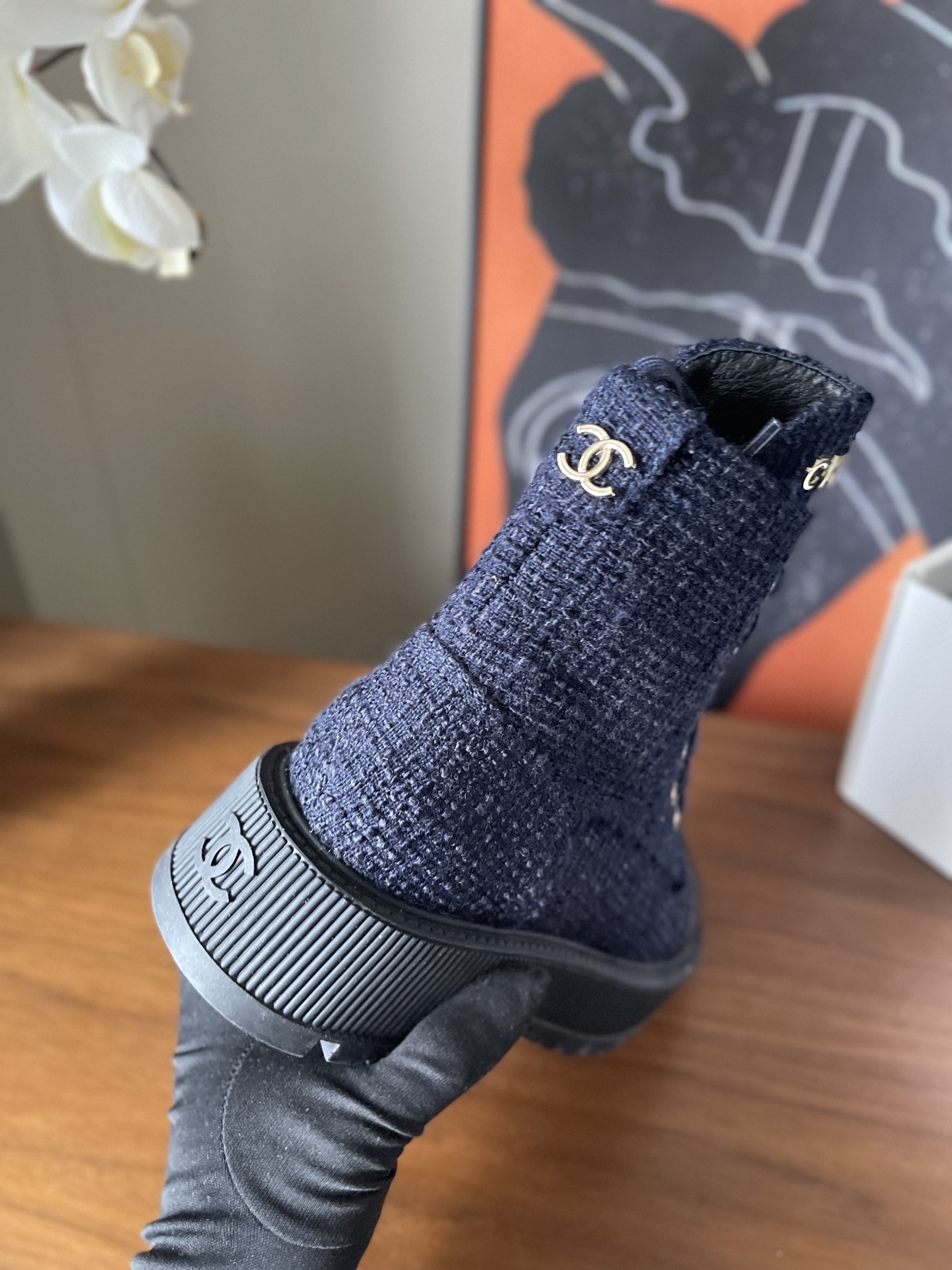 Pair of Chanel navy blue tweed lace-up ankle boots with black leather toe caps and gold lettering on a wooden surface. - Hình 8