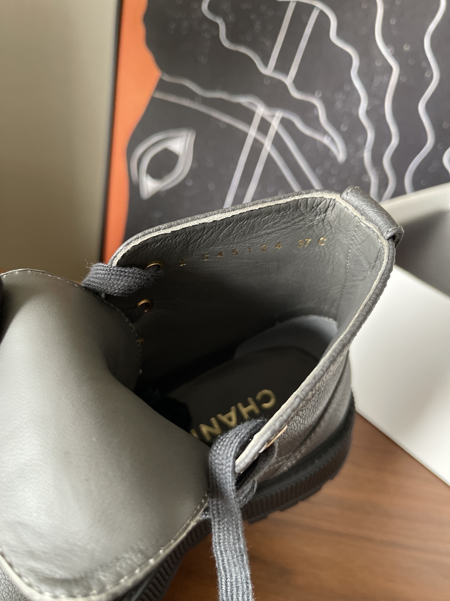 A pair of luxury grey pebbled leather ankle boots with black patent toe caps and thick black platform lug soles displayed on a wooden surface. - Hình 8