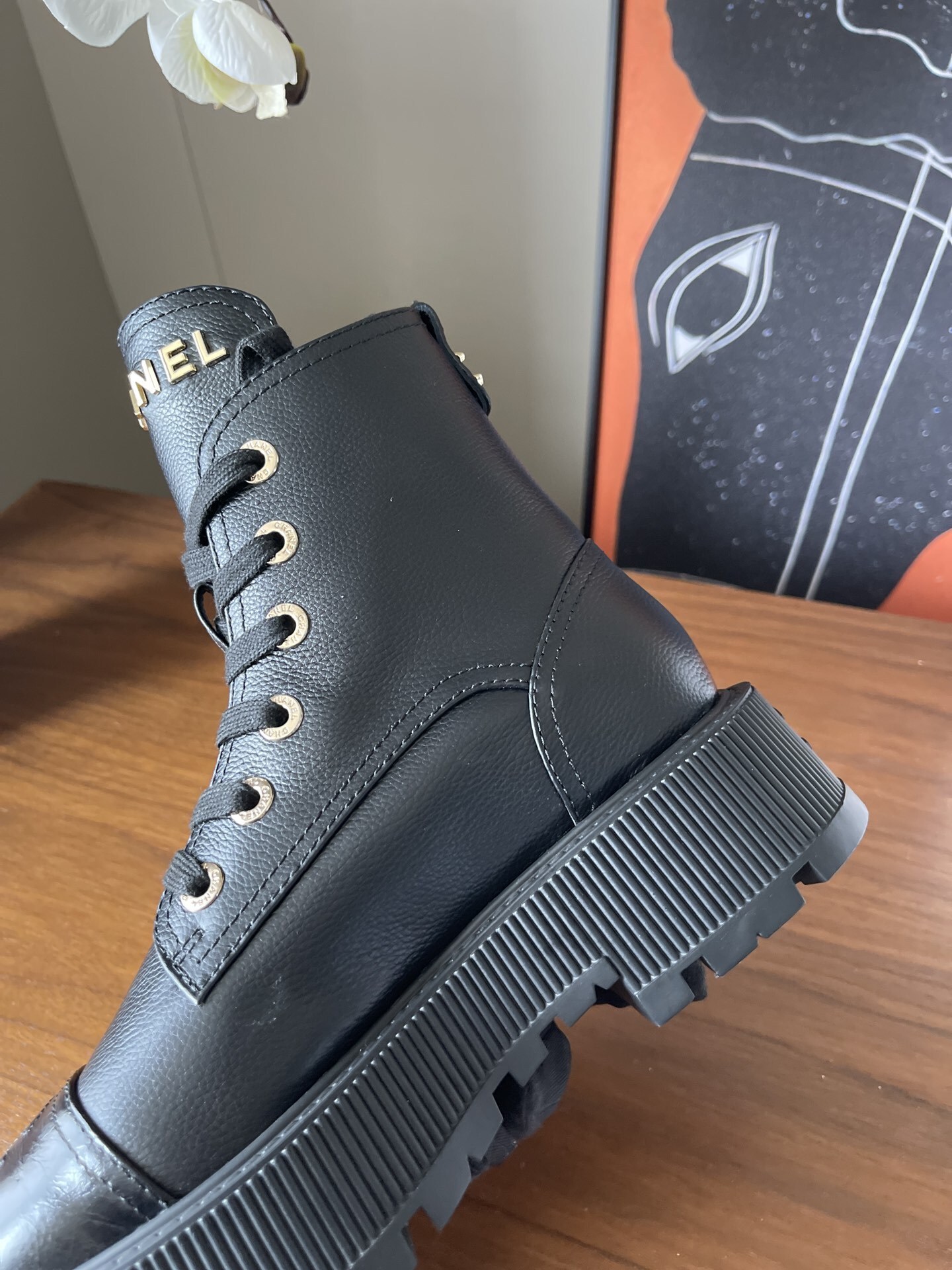 A pair of black Chanel grained leather combat boots with chunky platform soles and gold lettering on the tongue. - Hình 6