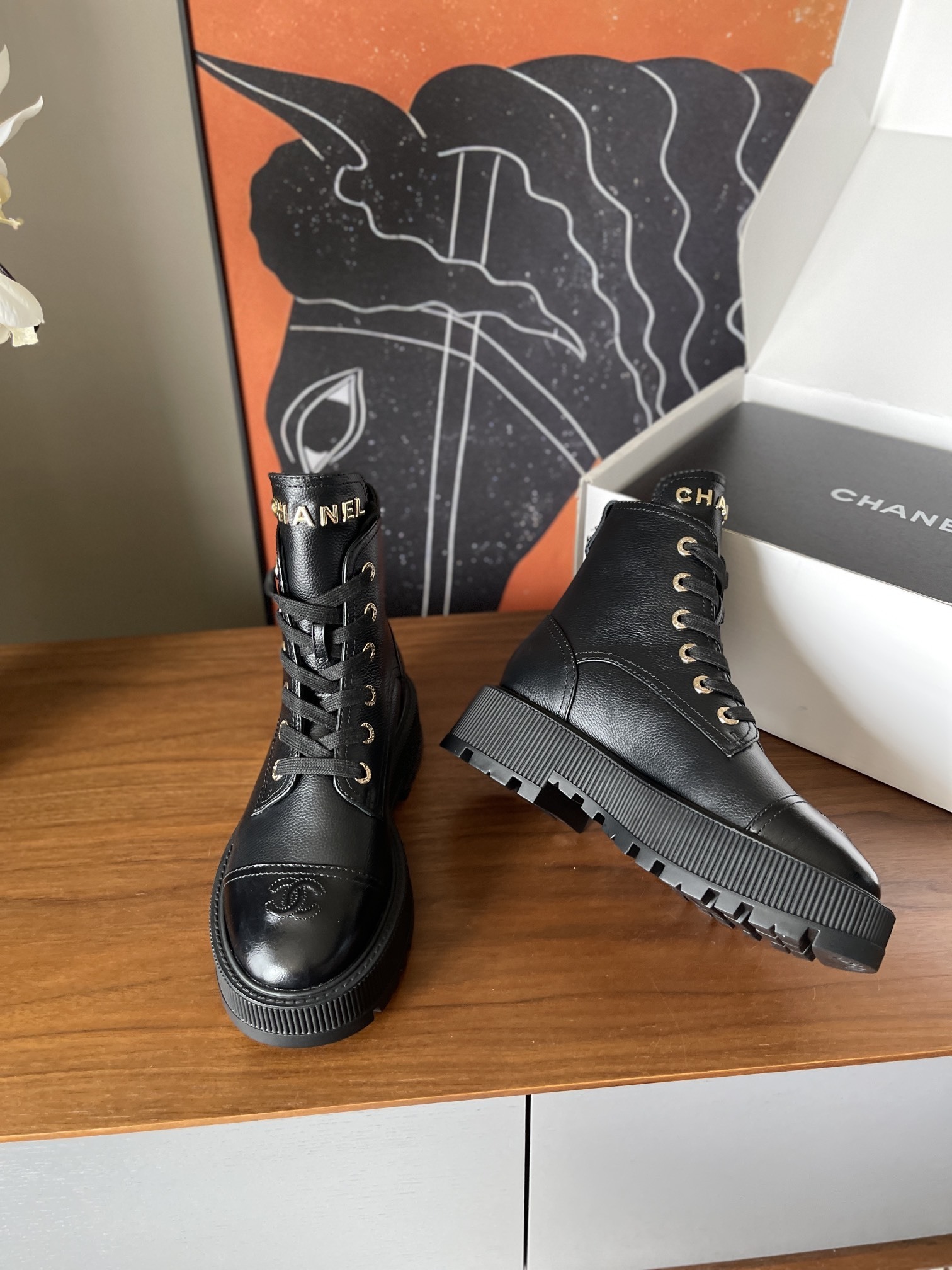 A pair of black Chanel grained leather combat boots with chunky platform soles and gold lettering on the tongue. - Hình 4