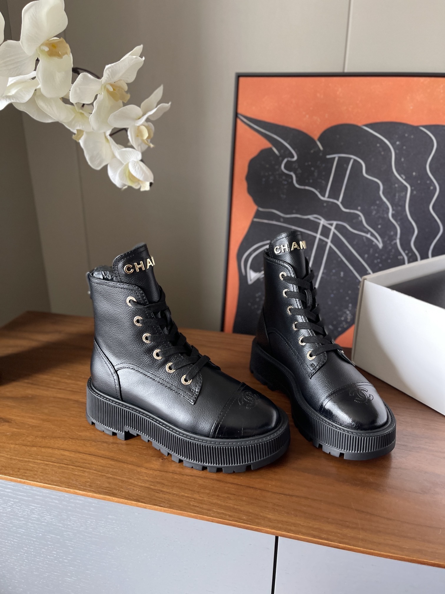 A pair of black Chanel grained leather combat boots with chunky platform soles and gold lettering on the tongue. - Hình 3