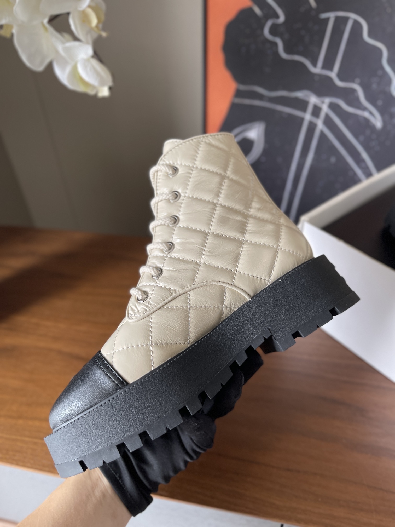 Pair of luxury quilted beige leather combat boots with black toe caps and chunky platform soles displayed on a wooden surface. - Hình 8