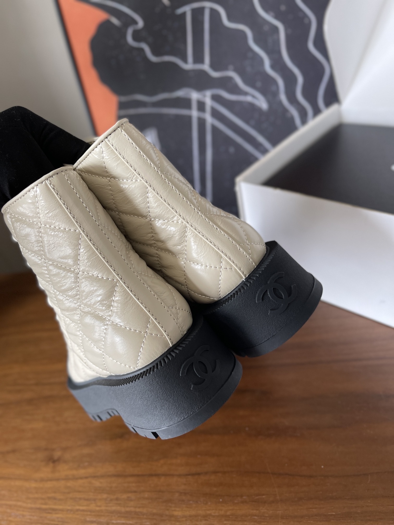 Pair of luxury quilted beige leather combat boots with black toe caps and chunky platform soles displayed on a wooden surface. - Hình 7