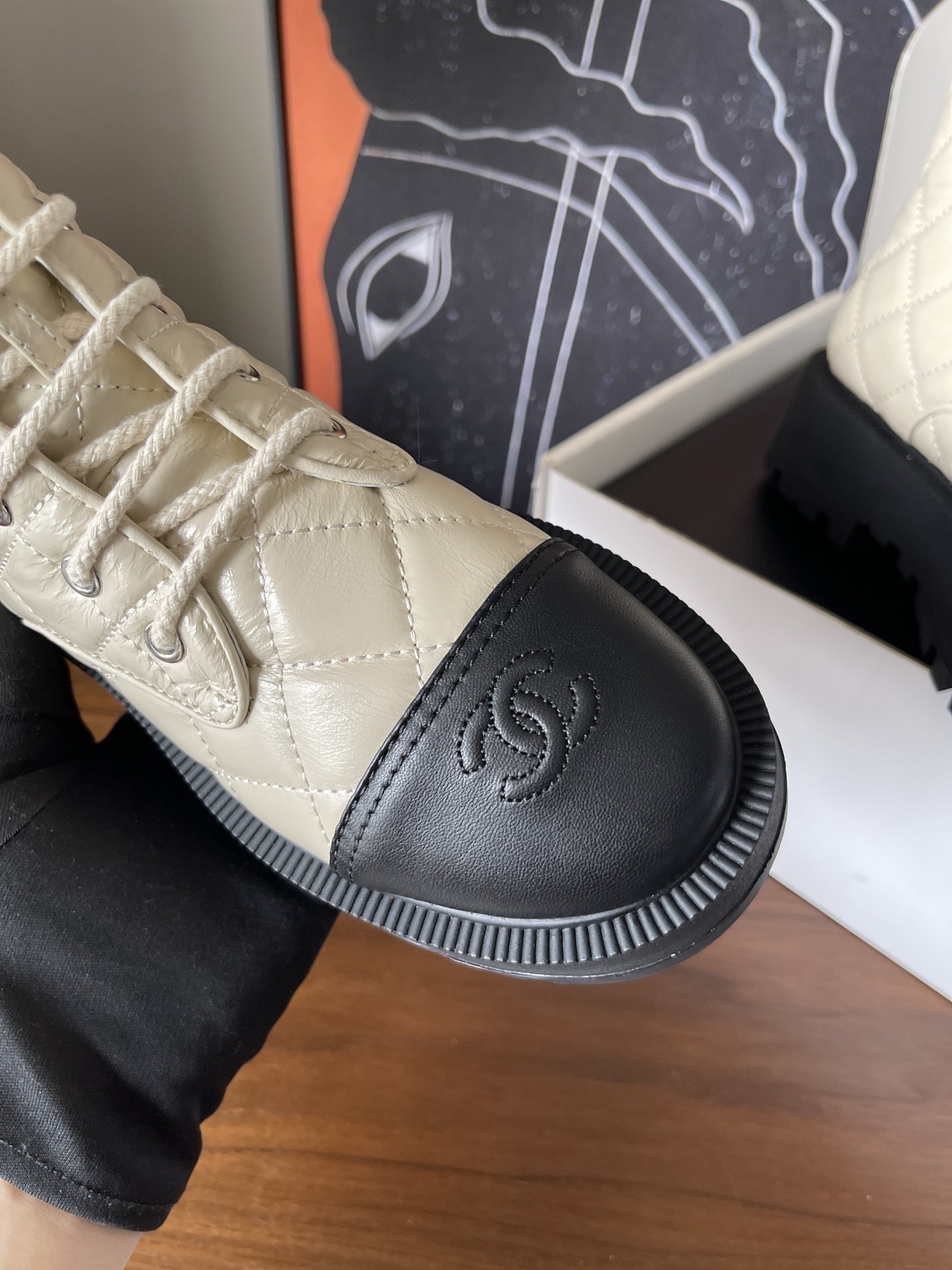 Pair of luxury quilted beige leather combat boots with black toe caps and chunky platform soles displayed on a wooden surface. - Hình 5