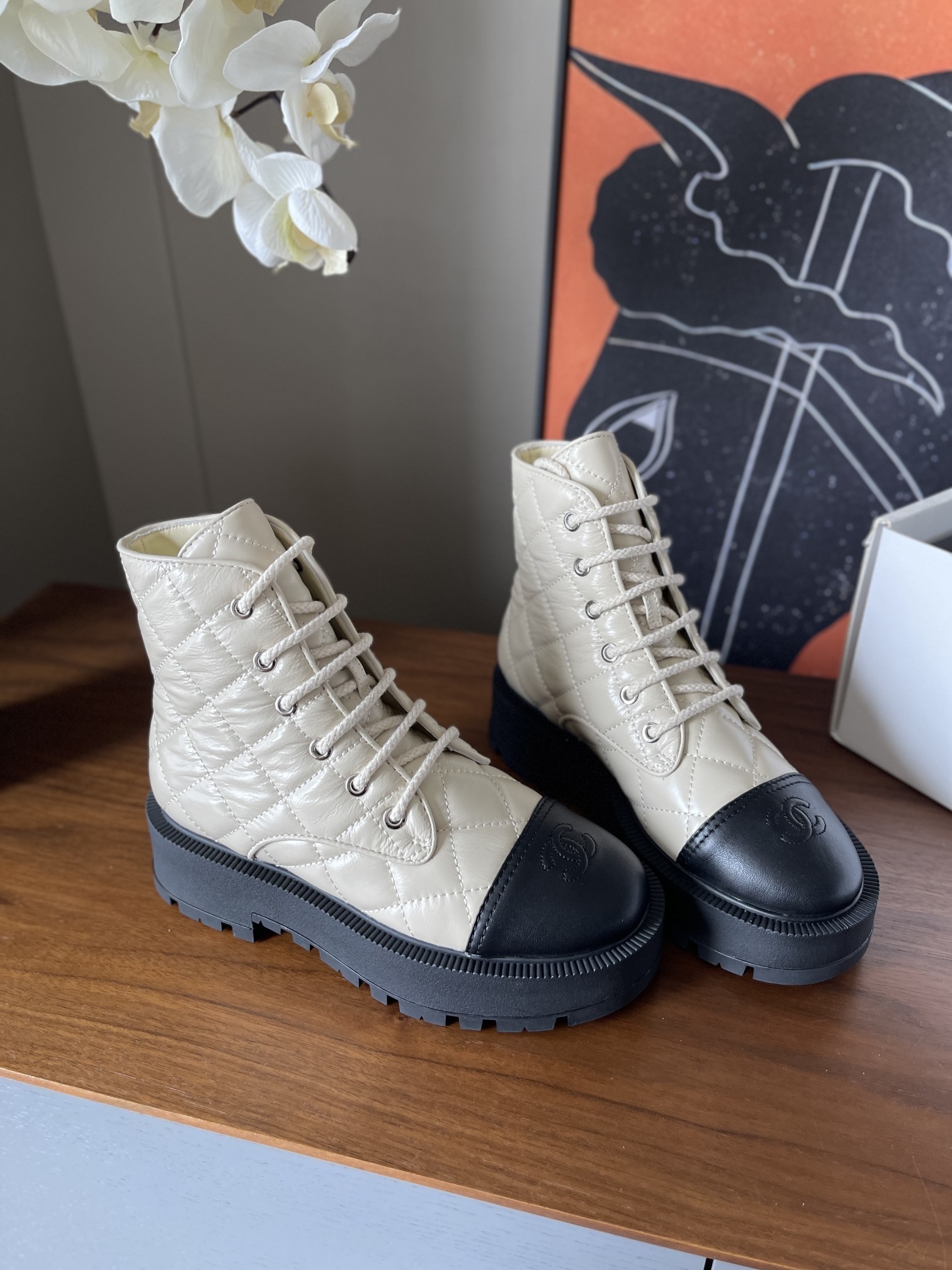 Pair of luxury quilted beige leather combat boots with black toe caps and chunky platform soles displayed on a wooden surface. - Hình 3
