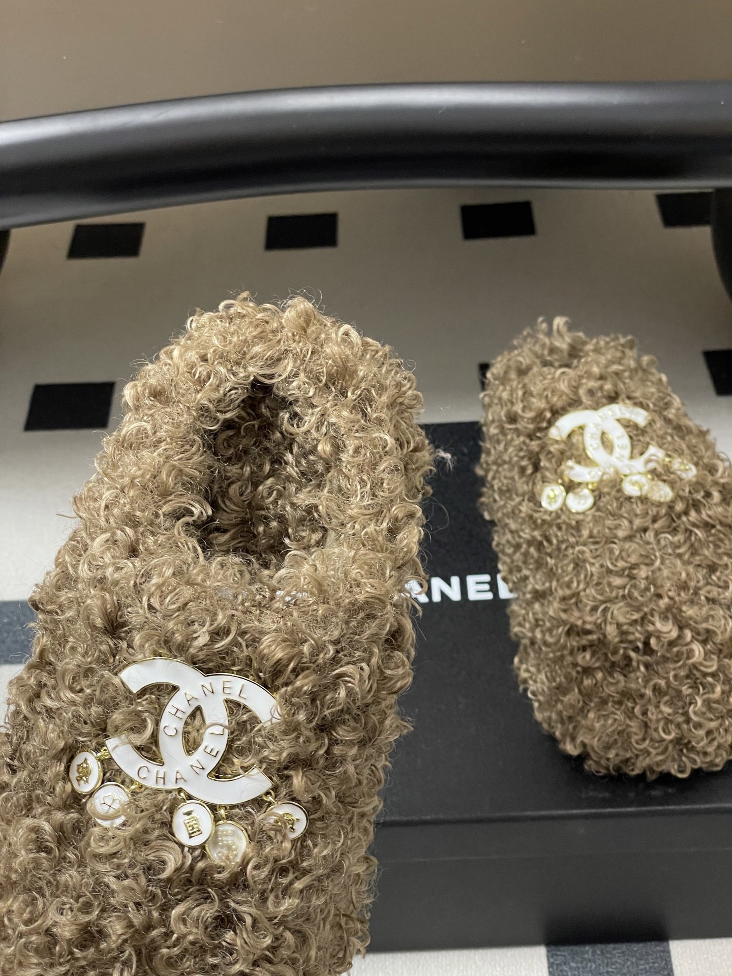 A pair of luxury brown curly faux fur slippers featuring a white logo and gold dangling charms - Hình 7