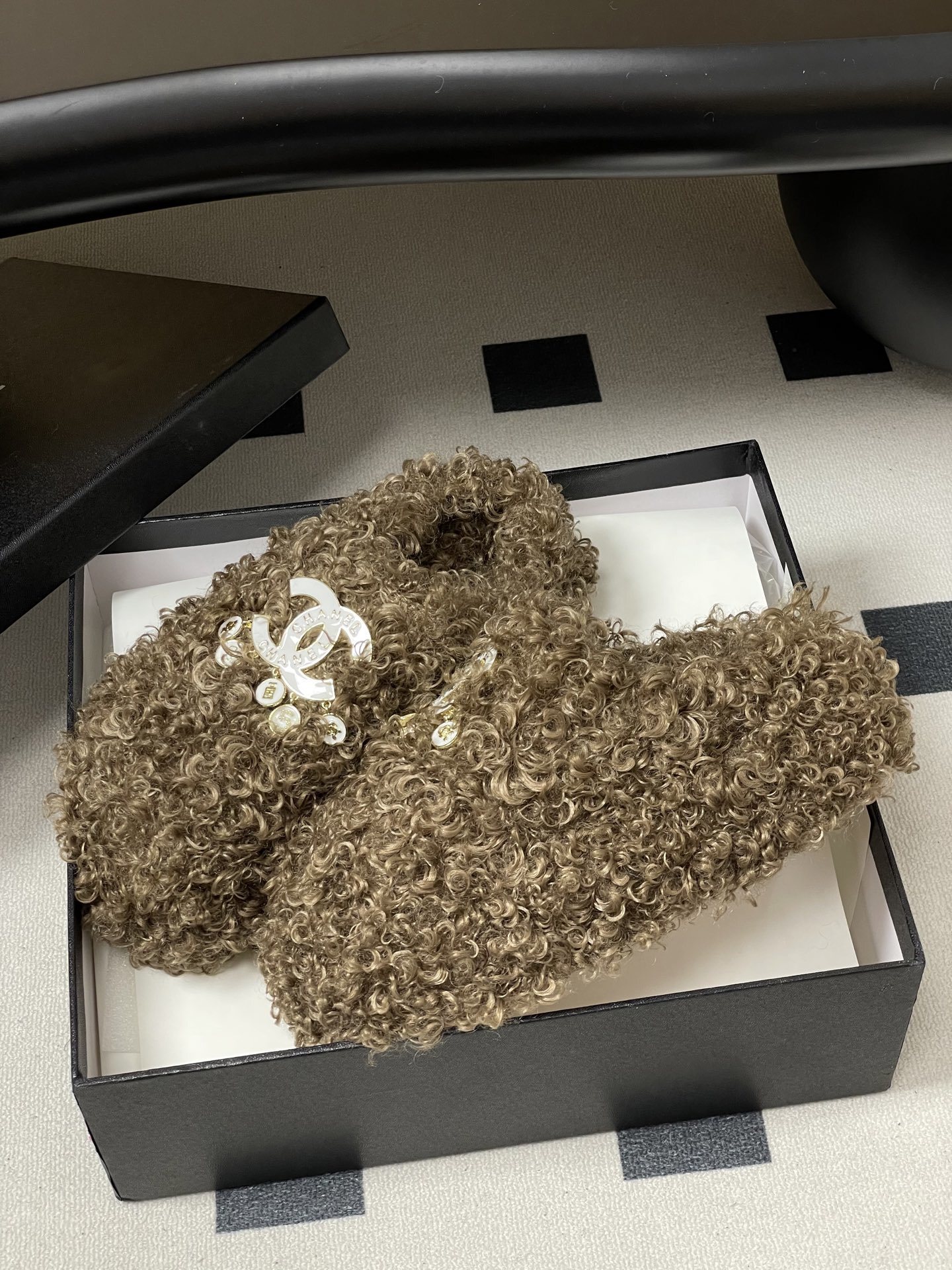 A pair of luxury brown curly faux fur slippers featuring a white logo and gold dangling charms - Hình 4