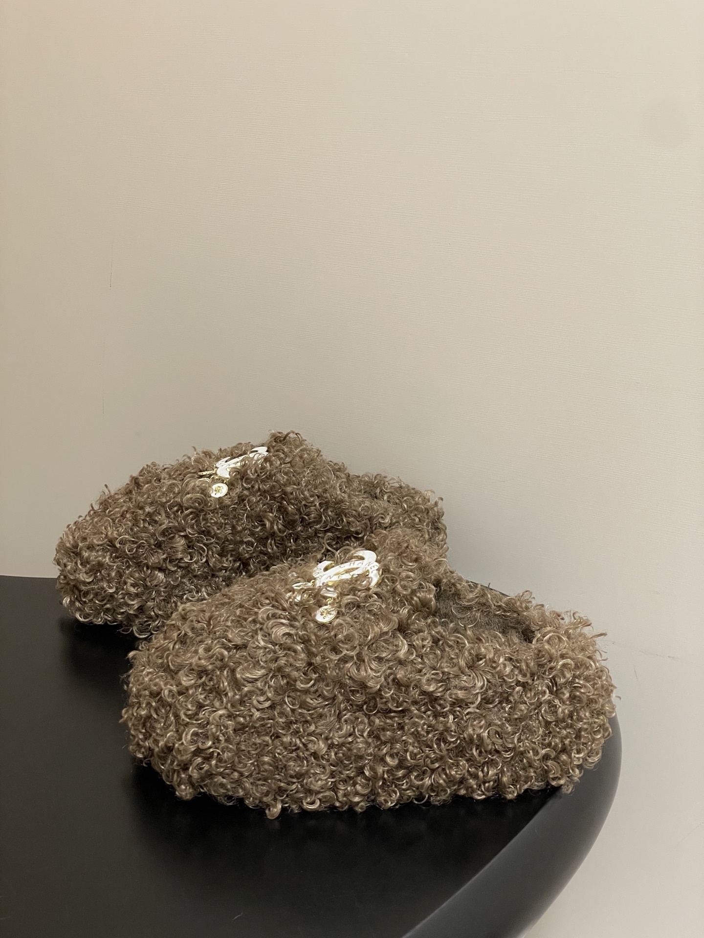 A pair of luxury brown curly faux fur slippers featuring a white logo and gold dangling charms - Hình 3