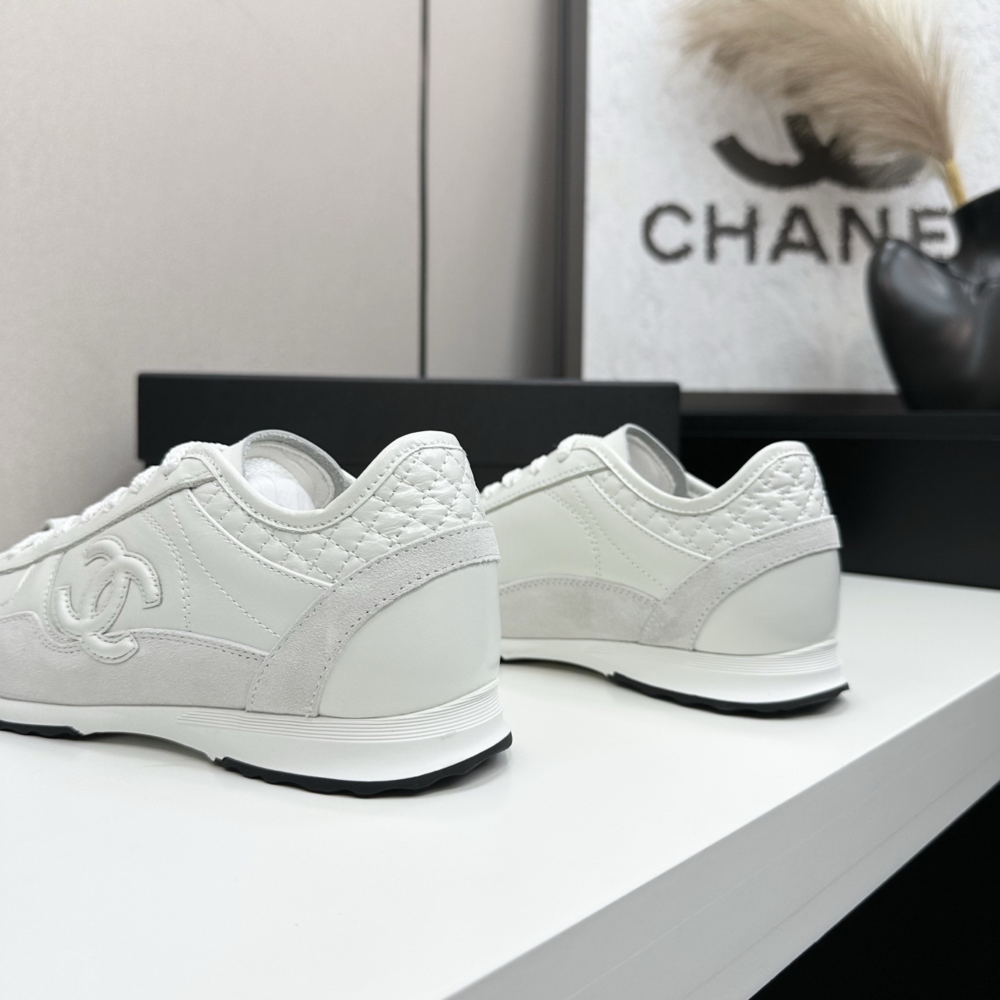Side view of white Chanel low-top sneakers featuring leather and suede panels with the iconic CC logo on a black box. - Hình 7