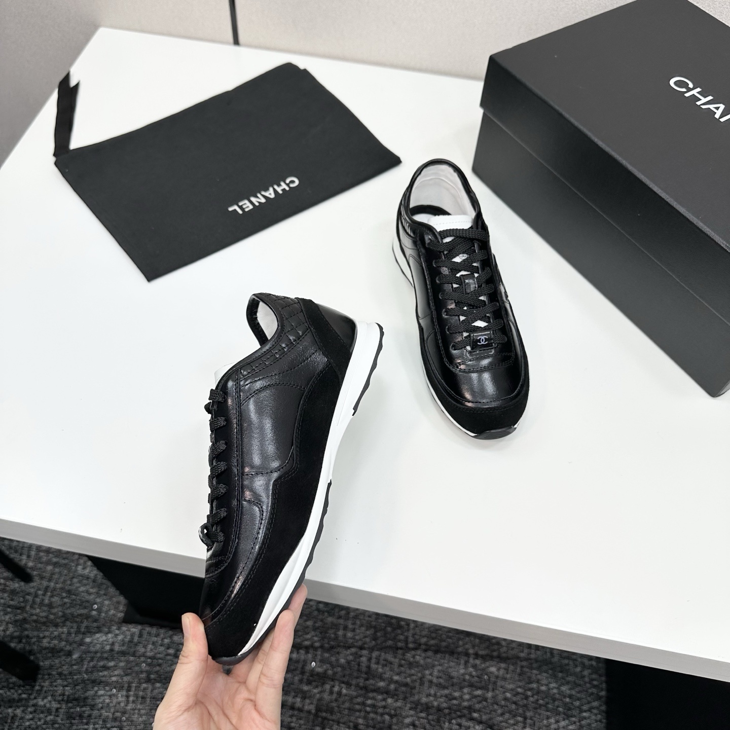 Close-up of Chanel black leather and suede sneakers with white soles and CC logo on a designer box - Hình 8