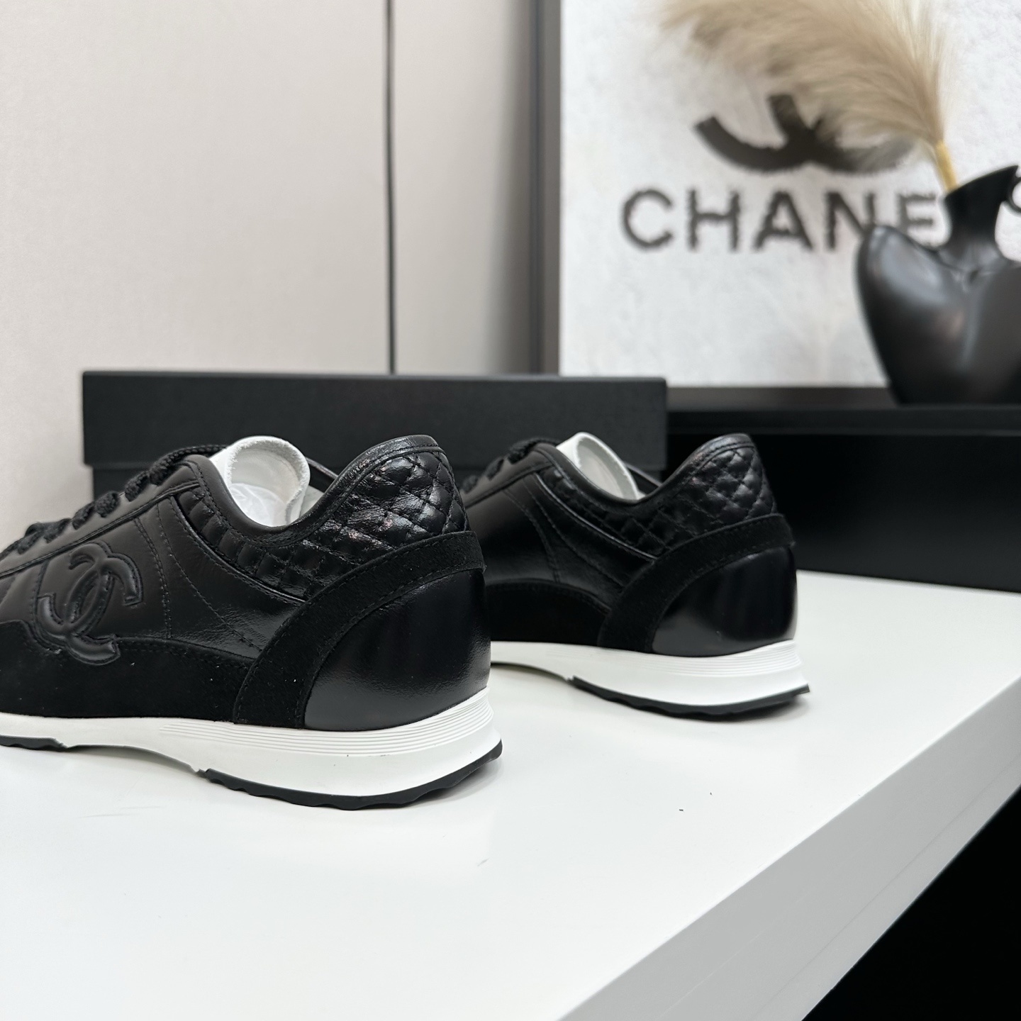 Close-up of Chanel black leather and suede sneakers with white soles and CC logo on a designer box - Hình 7