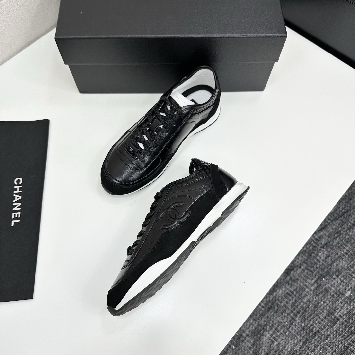 Close-up of Chanel black leather and suede sneakers with white soles and CC logo on a designer box - Hình 6