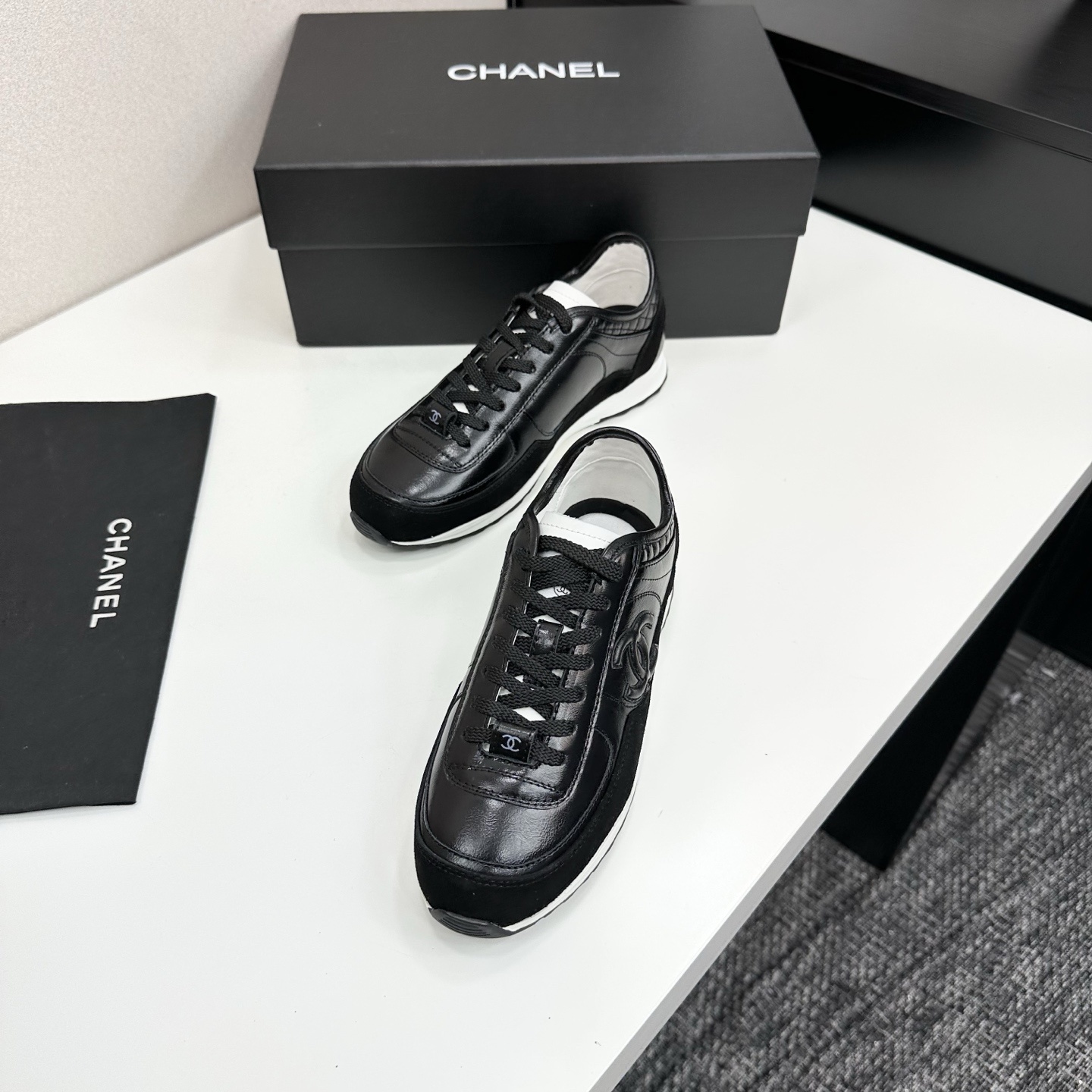 Close-up of Chanel black leather and suede sneakers with white soles and CC logo on a designer box - Hình 5