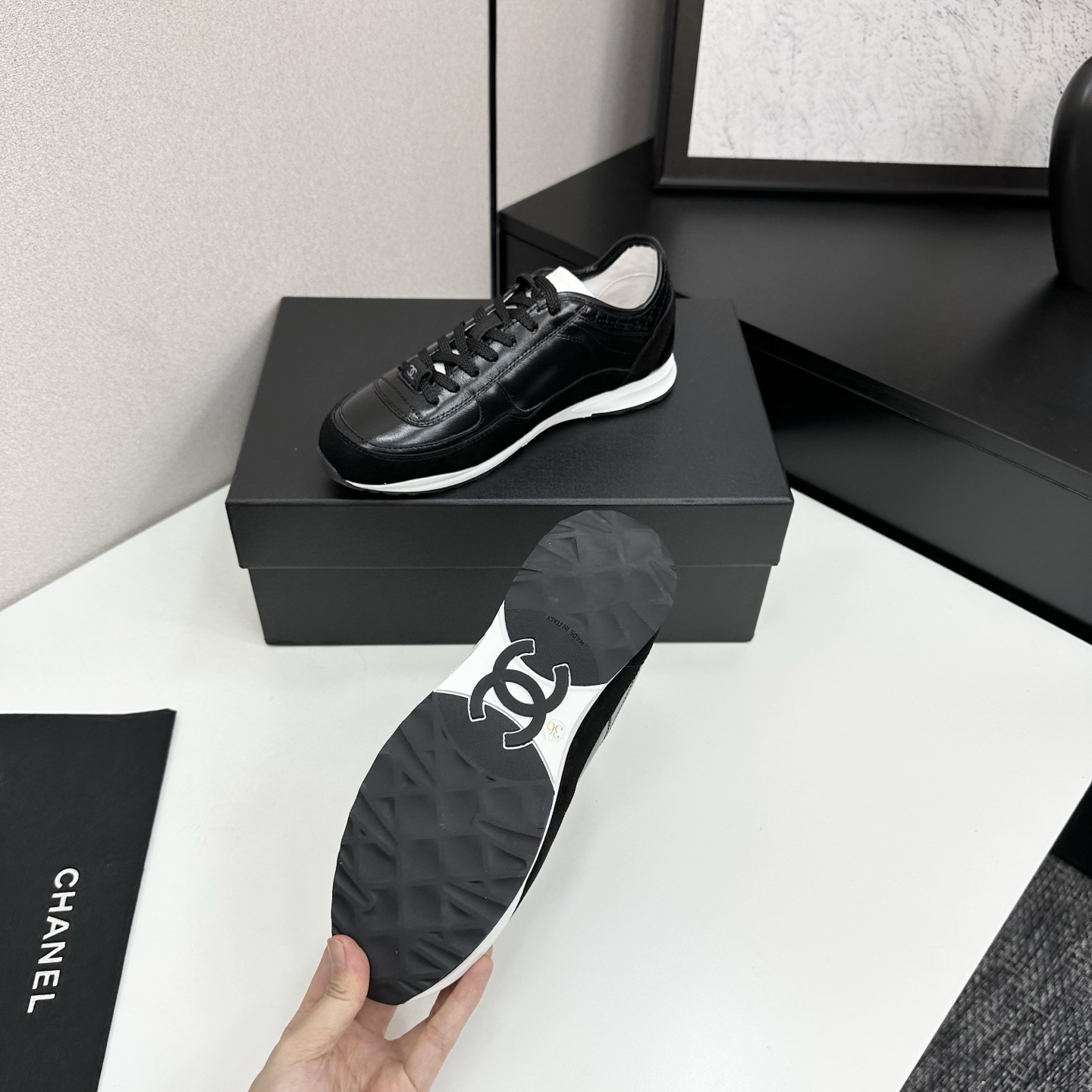 Close-up of Chanel black leather and suede sneakers with white soles and CC logo on a designer box - Hình 4