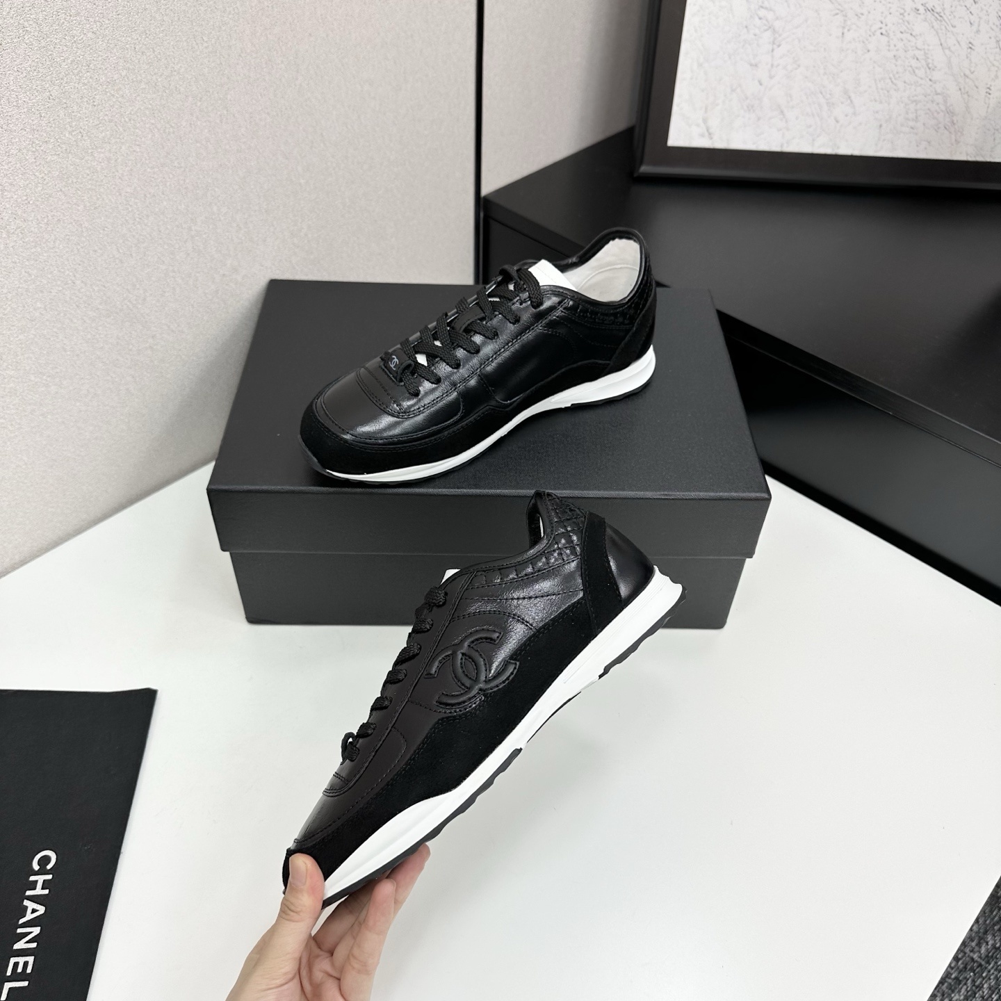 Close-up of Chanel black leather and suede sneakers with white soles and CC logo on a designer box - Hình 3
