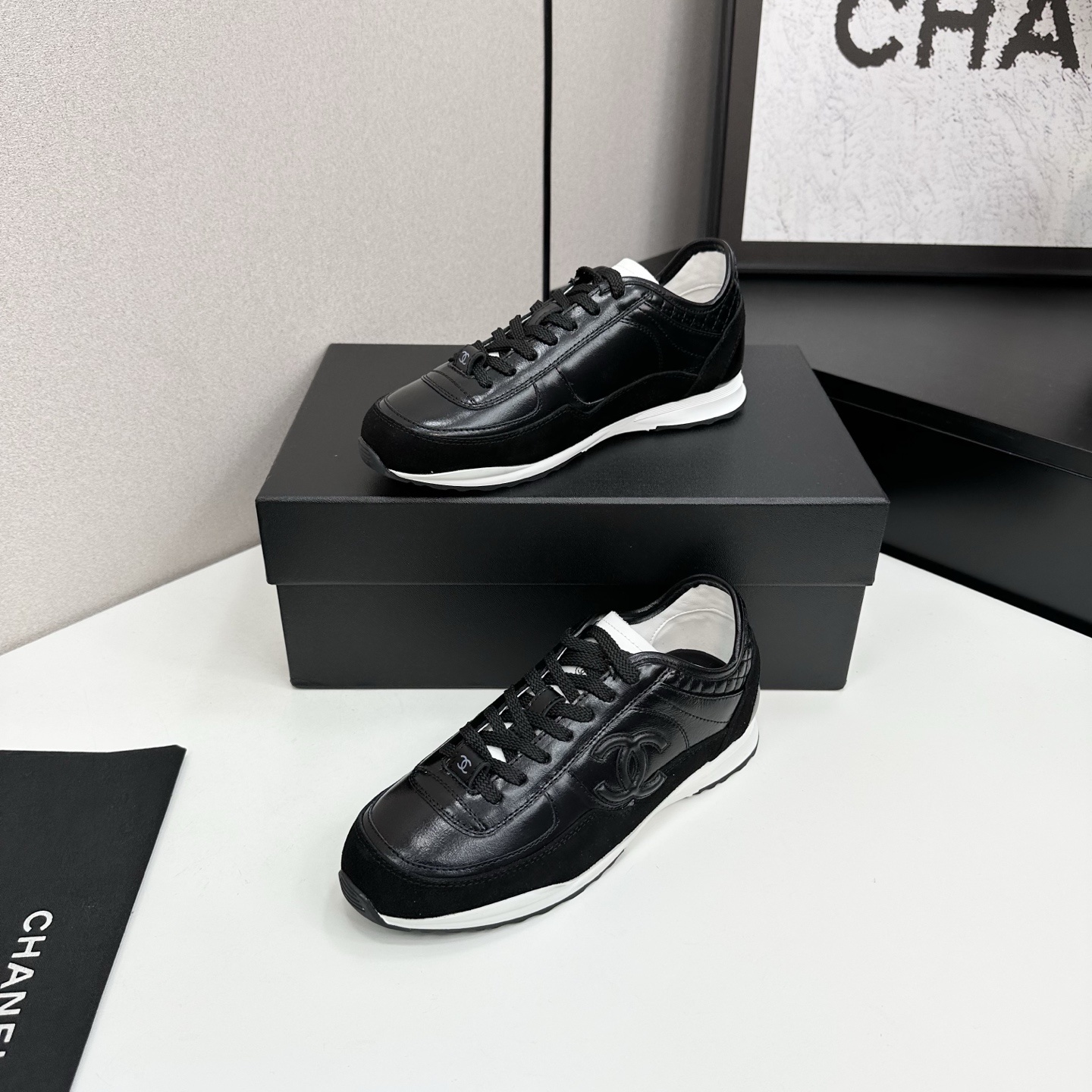 Close-up of Chanel black leather and suede sneakers with white soles and CC logo on a designer box - Hình 2