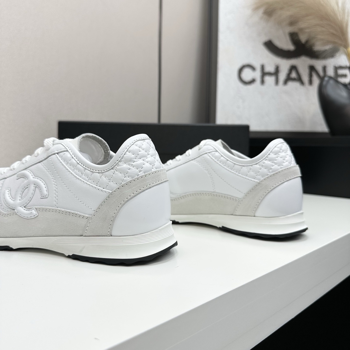 Side view of luxury white Chanel sneakers with quilted leather and interlocking CC logo on a black box. - Hình 6