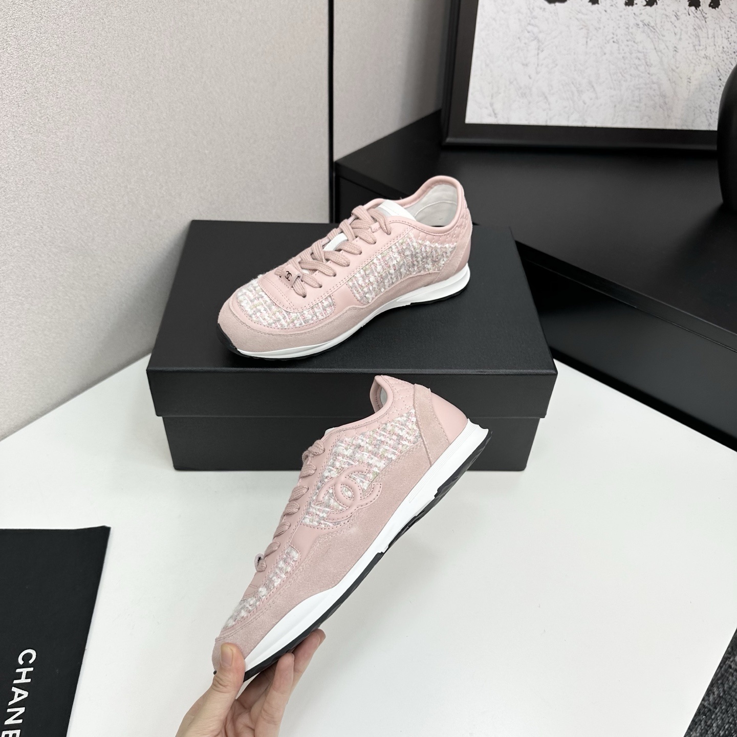 Side view of luxury blush pink sneakers featuring tweed fabric panels and interlocking logo on a black box. - Hình 3