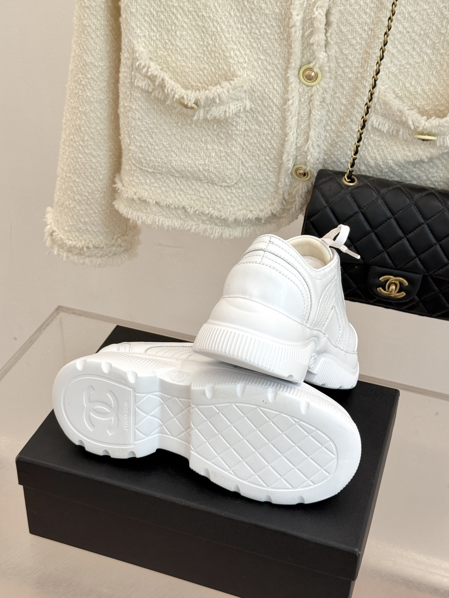 A pair of luxury white leather platform sneakers with embossed logo sitting on a black box. - Hình 9