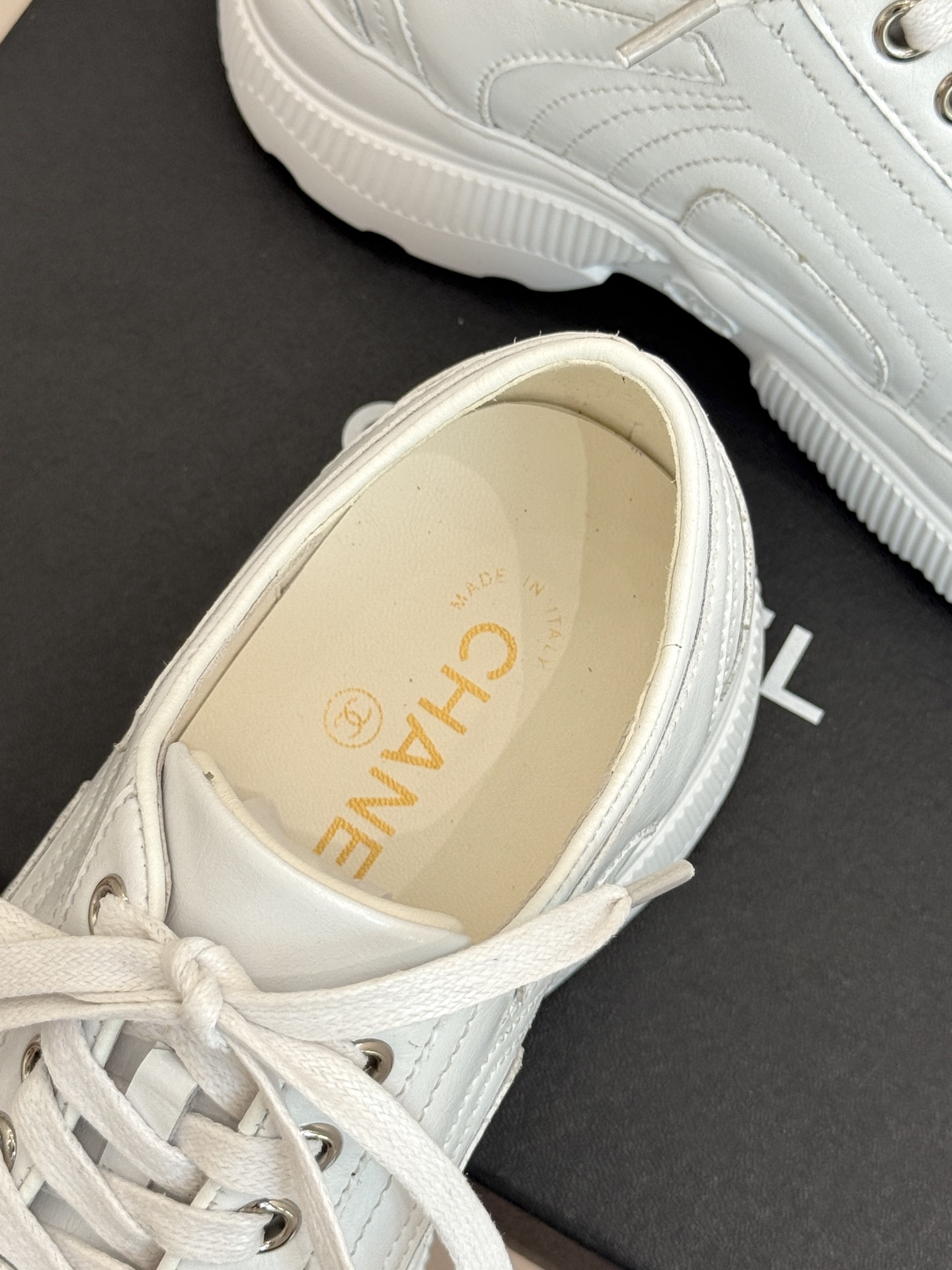 A pair of luxury white leather platform sneakers with embossed logo sitting on a black box. - Hình 8