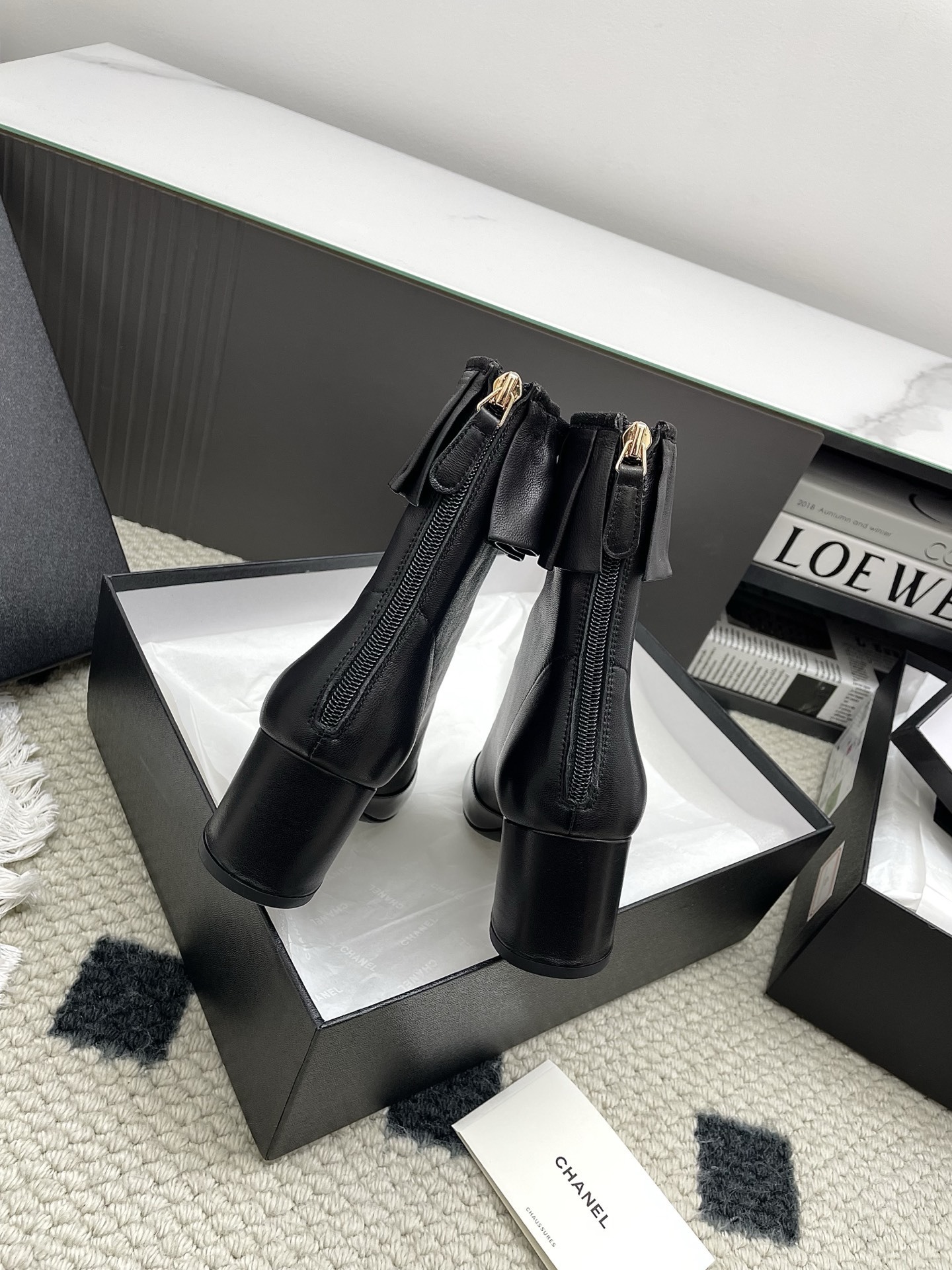 Pair of black Chanel leather ankle boots with ruffle trim and patent leather toe cap on a white surface. - Hình 6