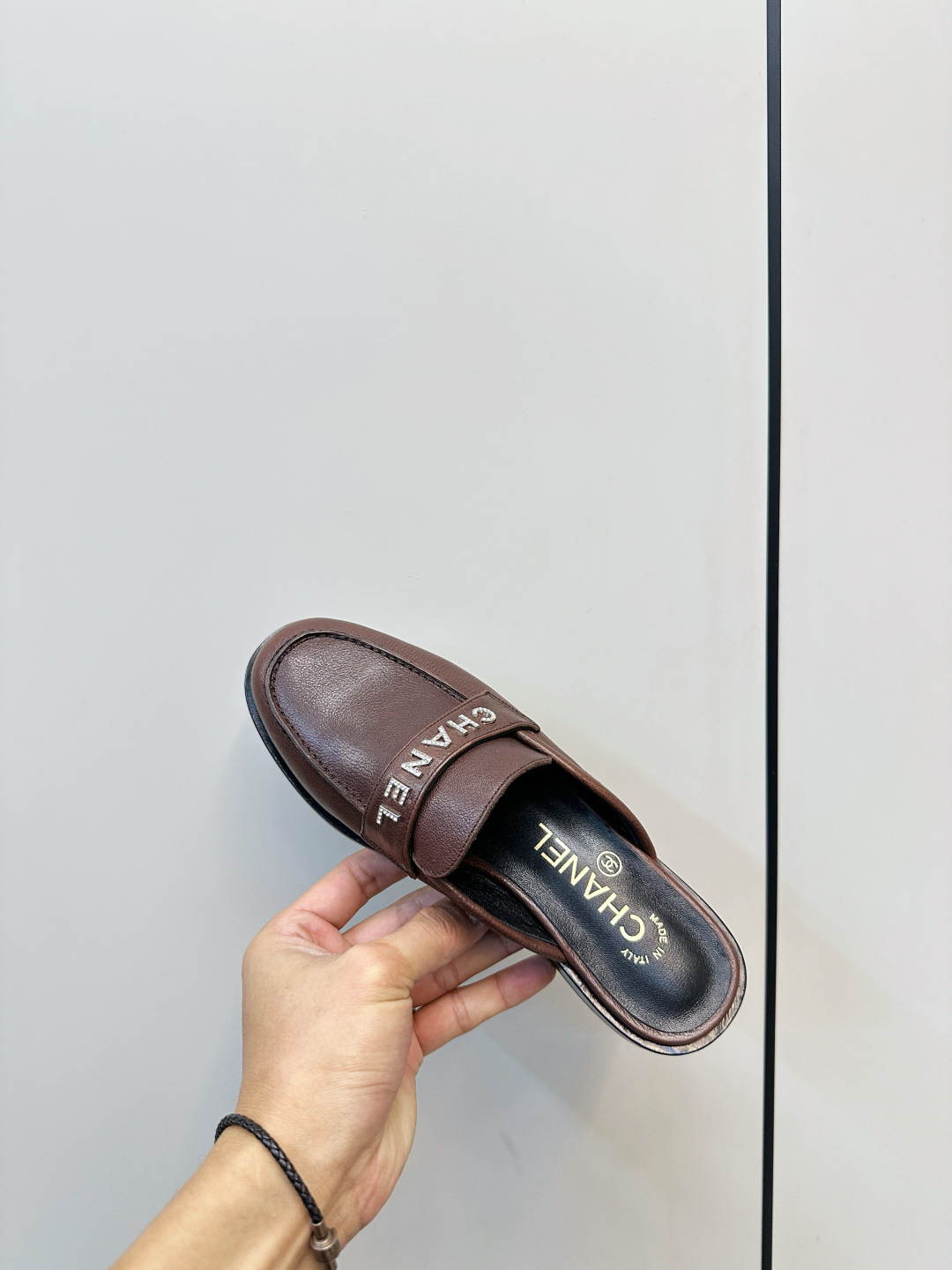 Pair of brown Chanel leather mules with crystal logo lettering displayed on a black box. - Hình 8