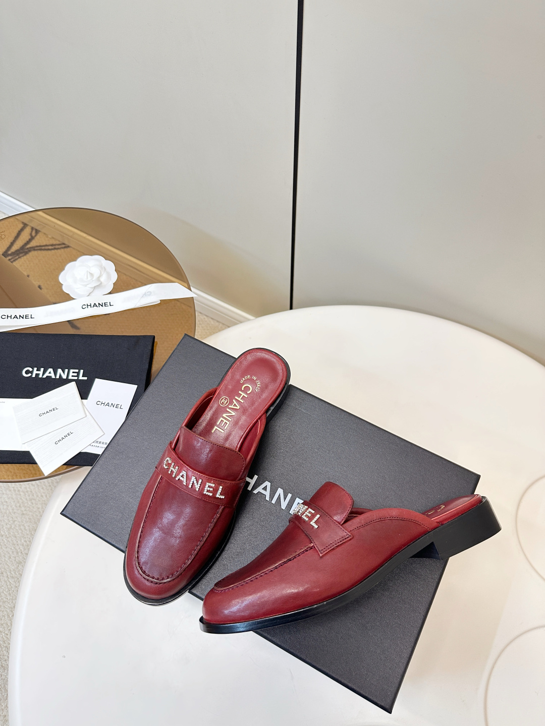 Luxury Chanel burgundy leather mules with crystal-embellished logo displayed on a black Chanel box. - Hình 9