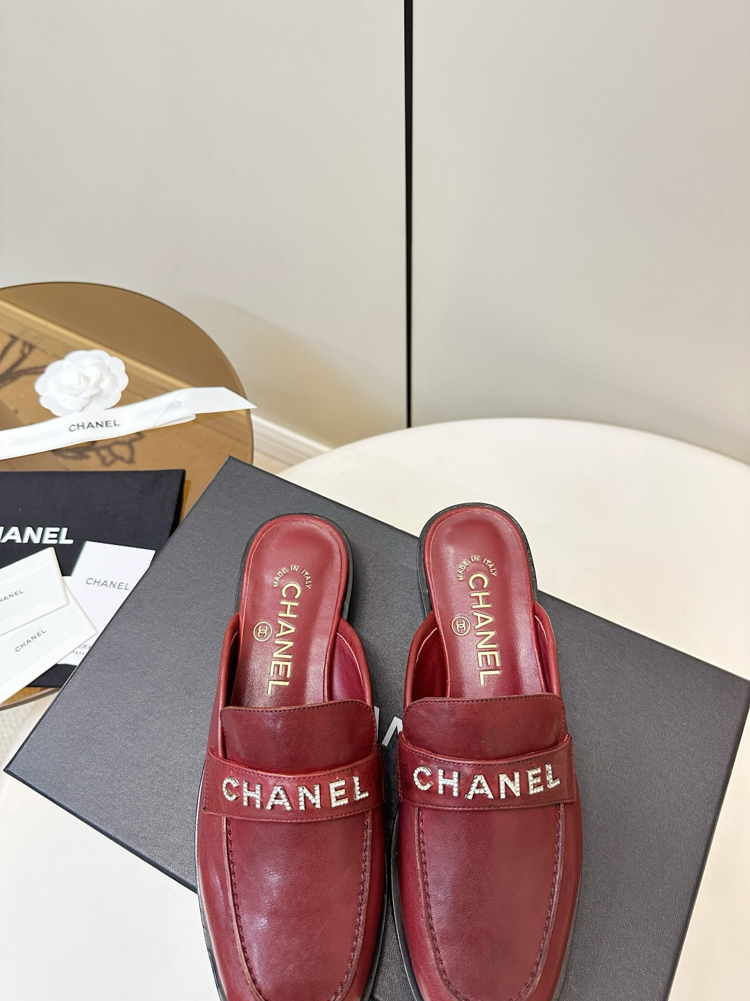 Luxury Chanel burgundy leather mules with crystal-embellished logo displayed on a black Chanel box. - Hình 8