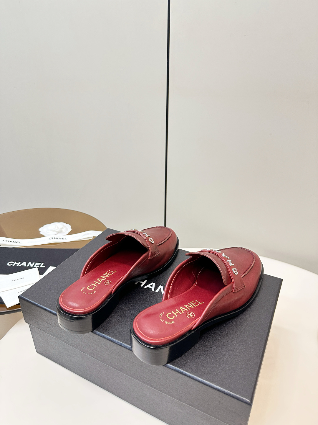 Luxury Chanel burgundy leather mules with crystal-embellished logo displayed on a black Chanel box. - Hình 4