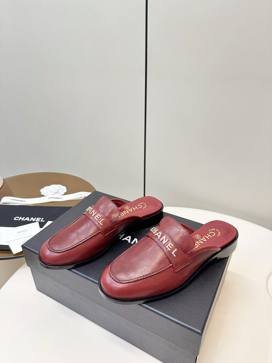 Luxury Chanel burgundy leather mules with crystal-embellished logo displayed on a black Chanel box. - Hình 2