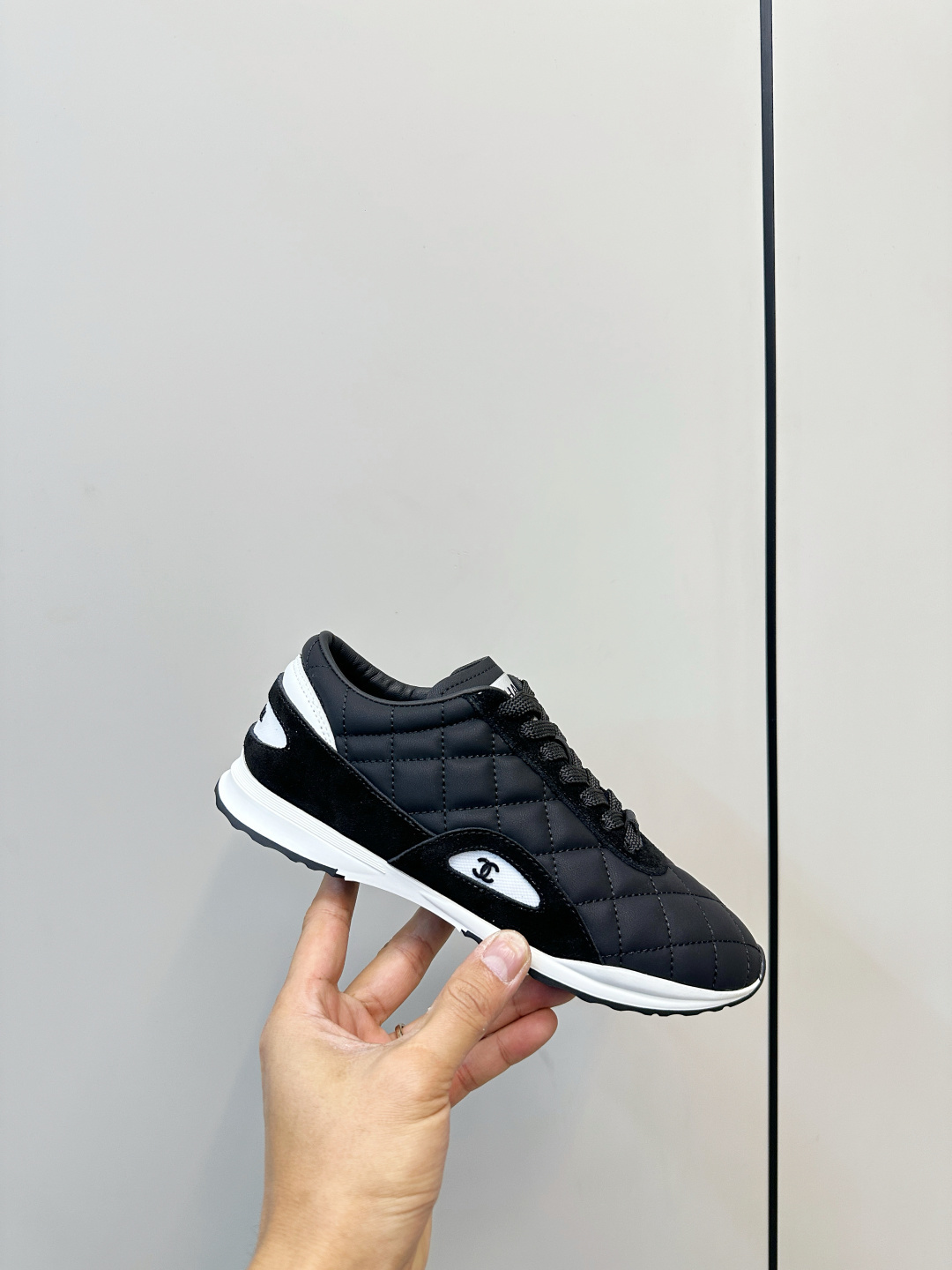 A pair of black Chanel quilted fabric sneakers with white soles and CC logo sitting on a black branded box. - Hình 6