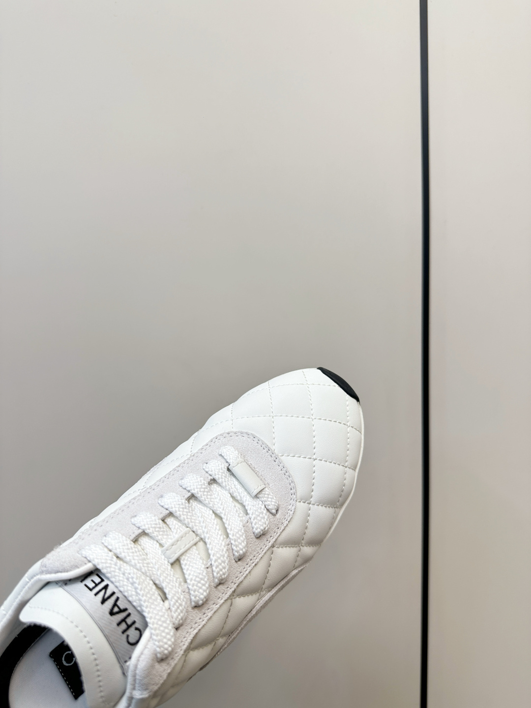 A pair of luxury white Chanel sneakers with a quilted pattern and CC logo resting on a black Chanel shoe box. - Hình 7