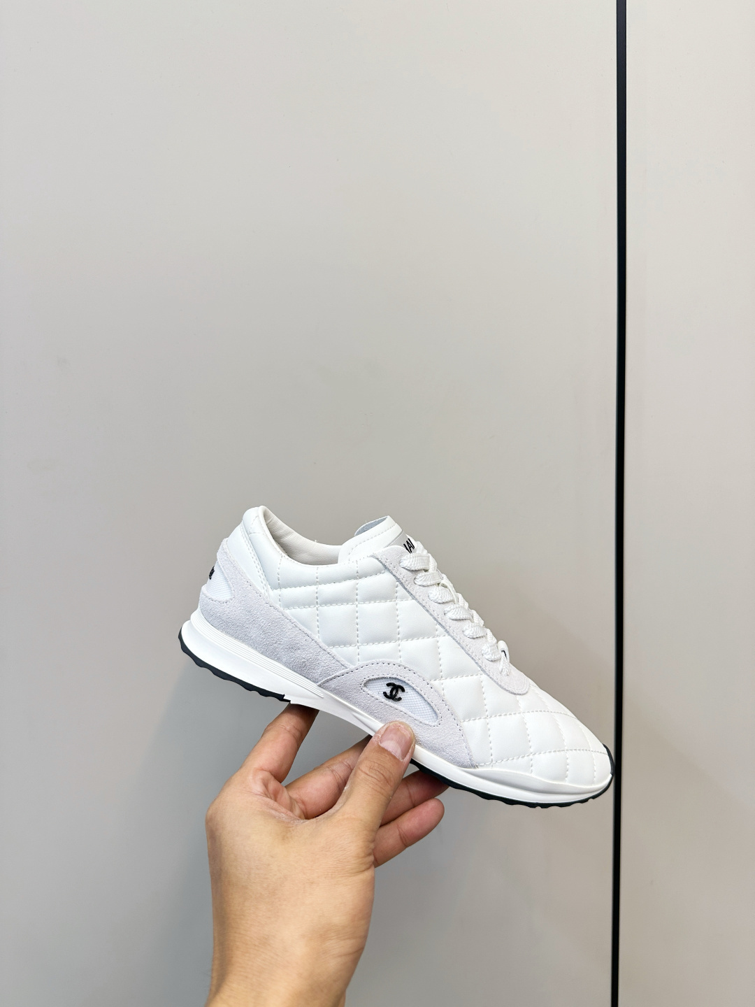 A pair of luxury white Chanel sneakers with a quilted pattern and CC logo resting on a black Chanel shoe box. - Hình 6