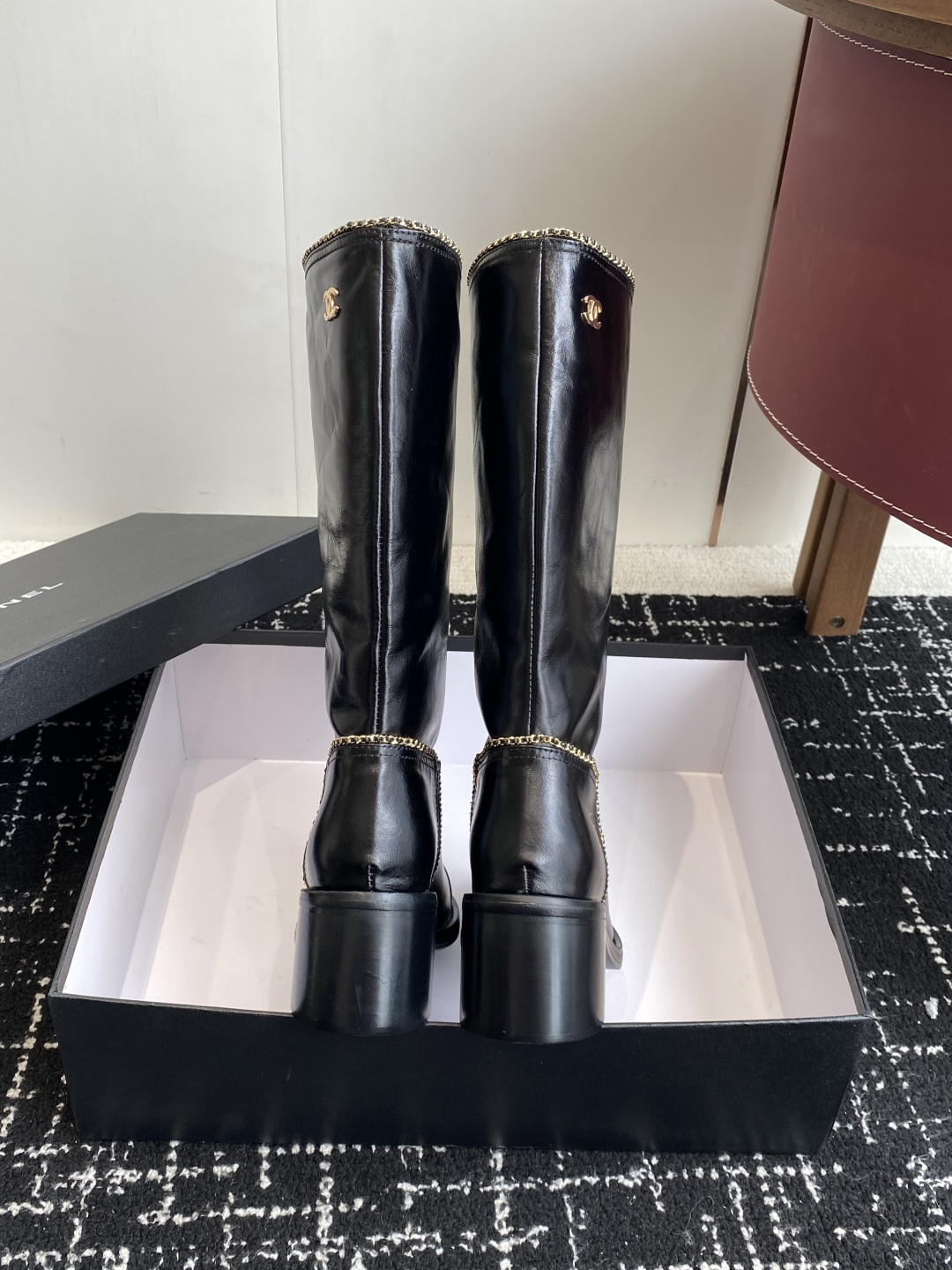 Pair of black Chanel leather knee-high boots with gold chain trim and embossed CC logo on the toe cap. - Hình 8
