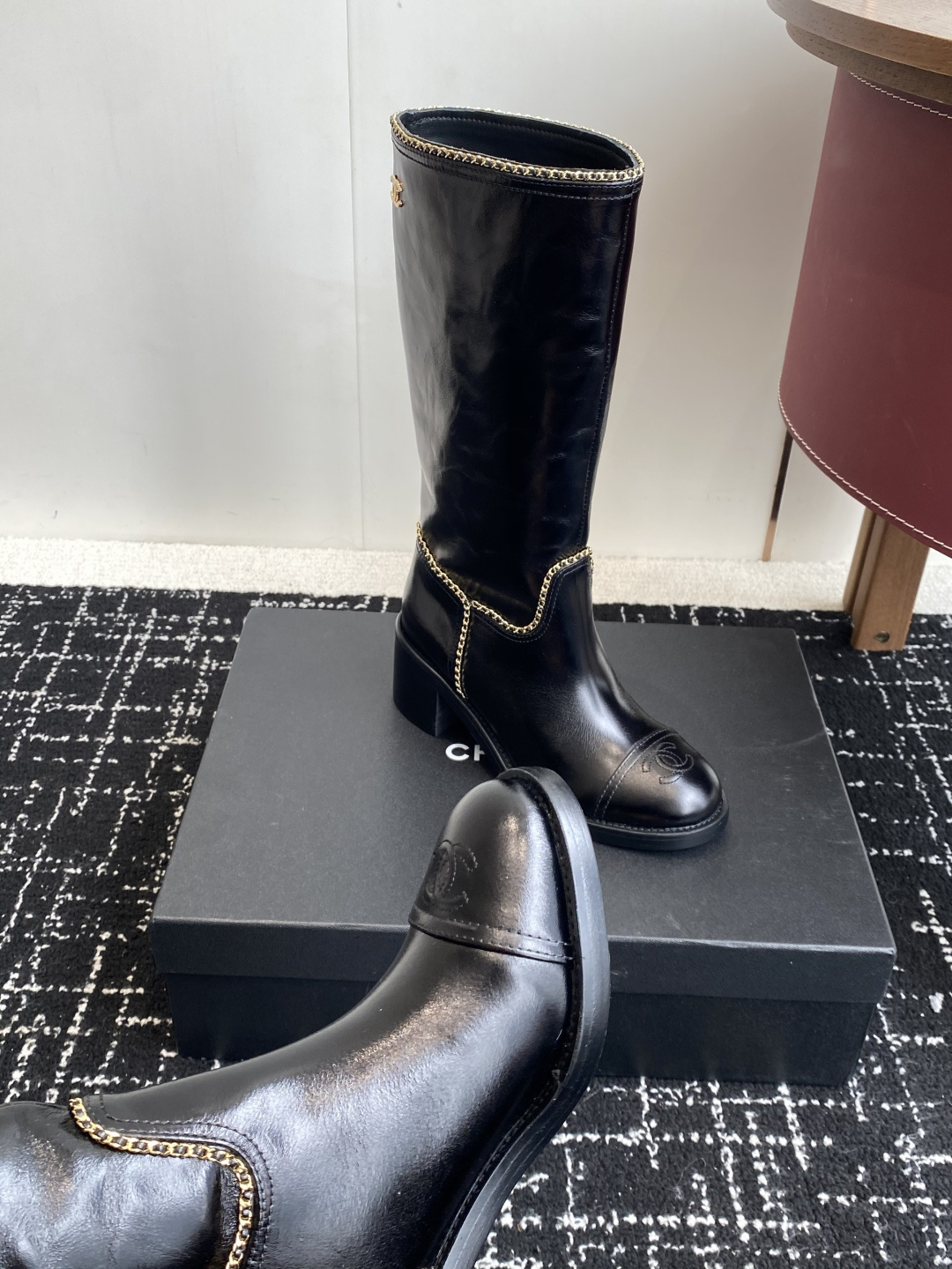 Pair of black Chanel leather knee-high boots with gold chain trim and embossed CC logo on the toe cap. - Hình 7