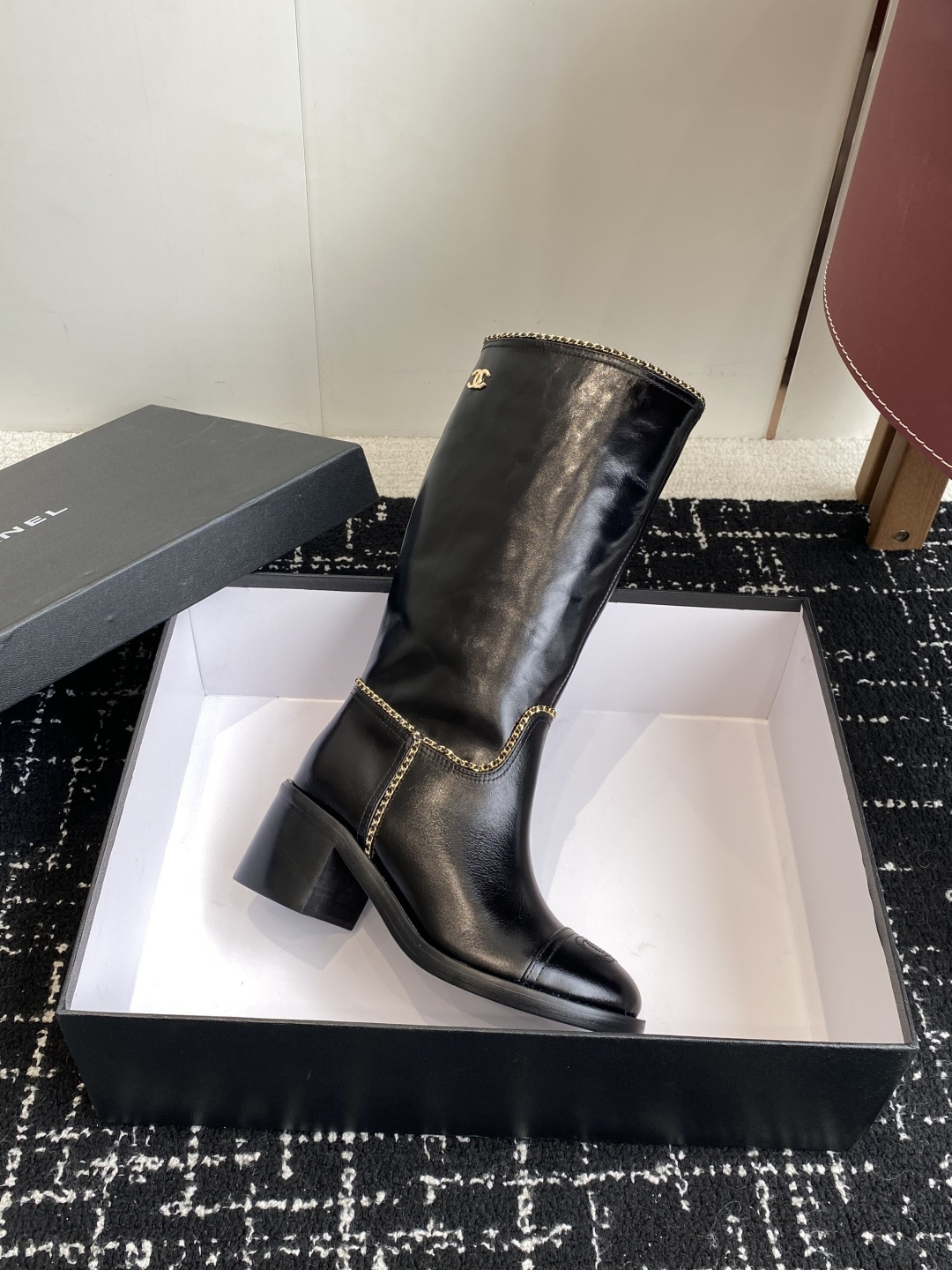 Pair of black Chanel leather knee-high boots with gold chain trim and embossed CC logo on the toe cap. - Hình 6