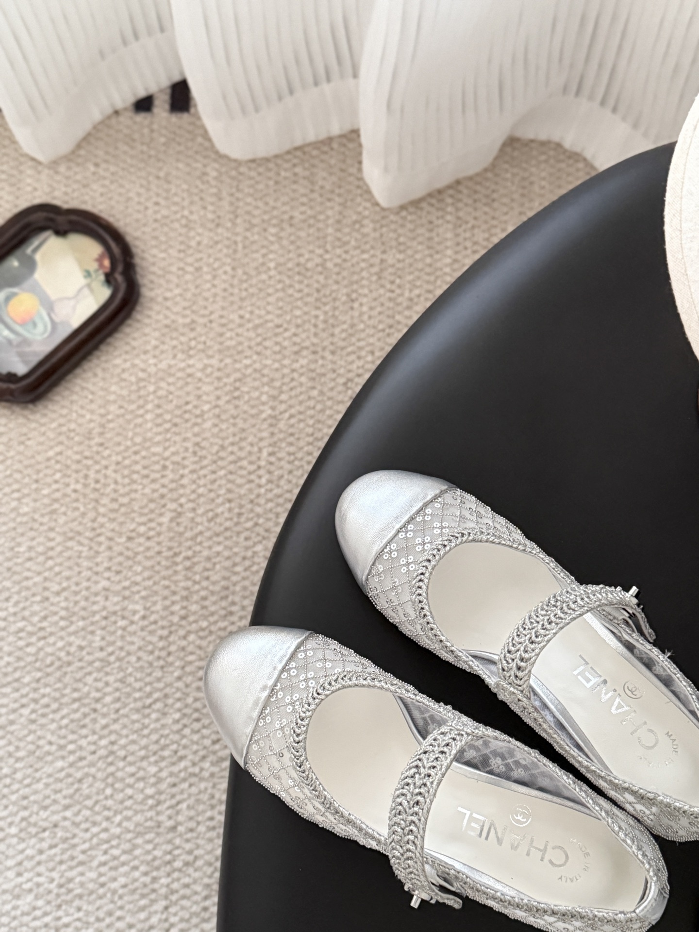 A pair of Chanel silver sequined mesh Mary Jane block heels next to a black Chanel shoe box on a dark surface. - Hình 7