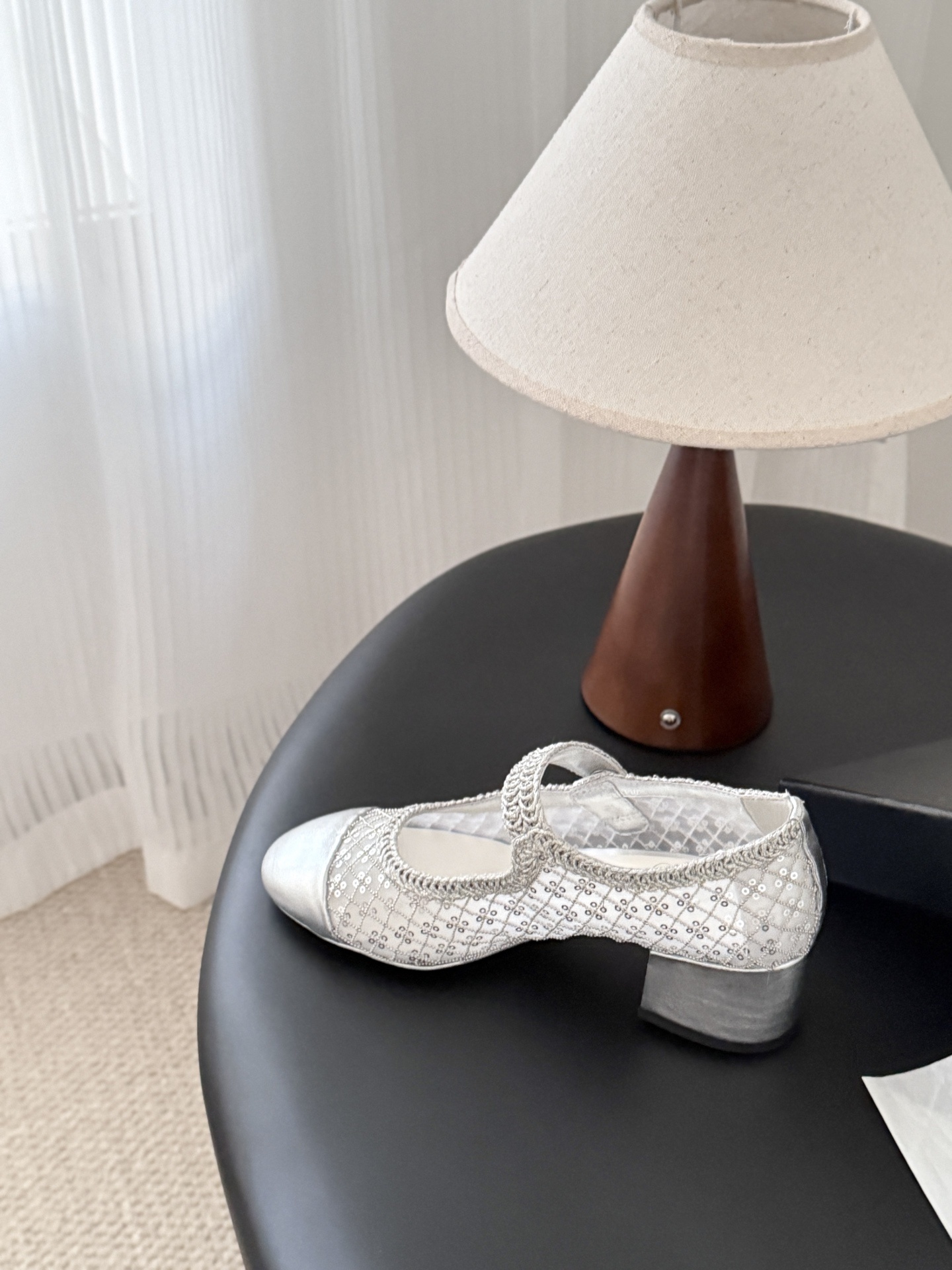 A pair of Chanel silver sequined mesh Mary Jane block heels next to a black Chanel shoe box on a dark surface. - Hình 4