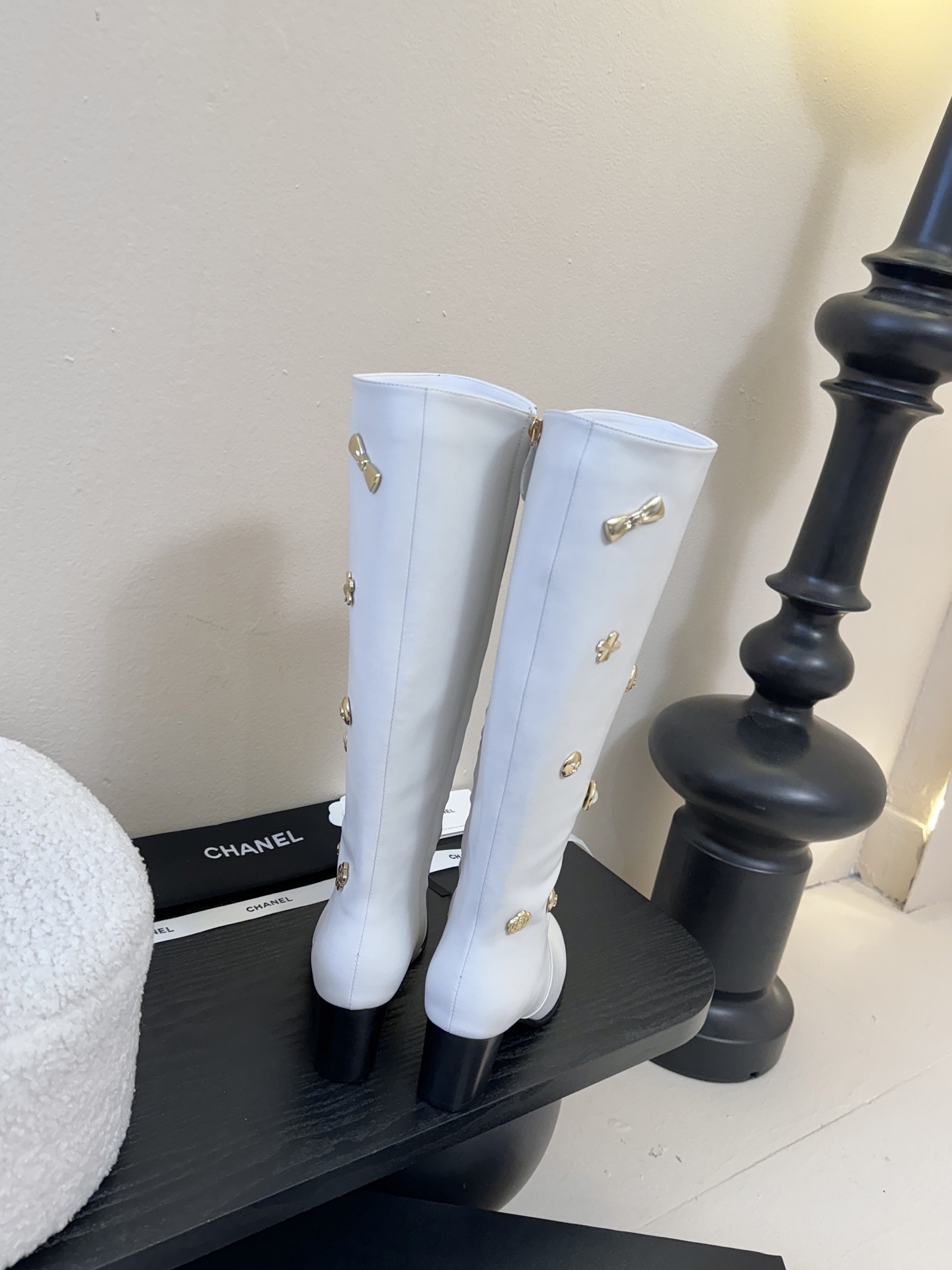Luxury Chanel white leather knee-high boots decorated with gold-tone CC logos and charms on a display stand. - Hình 7