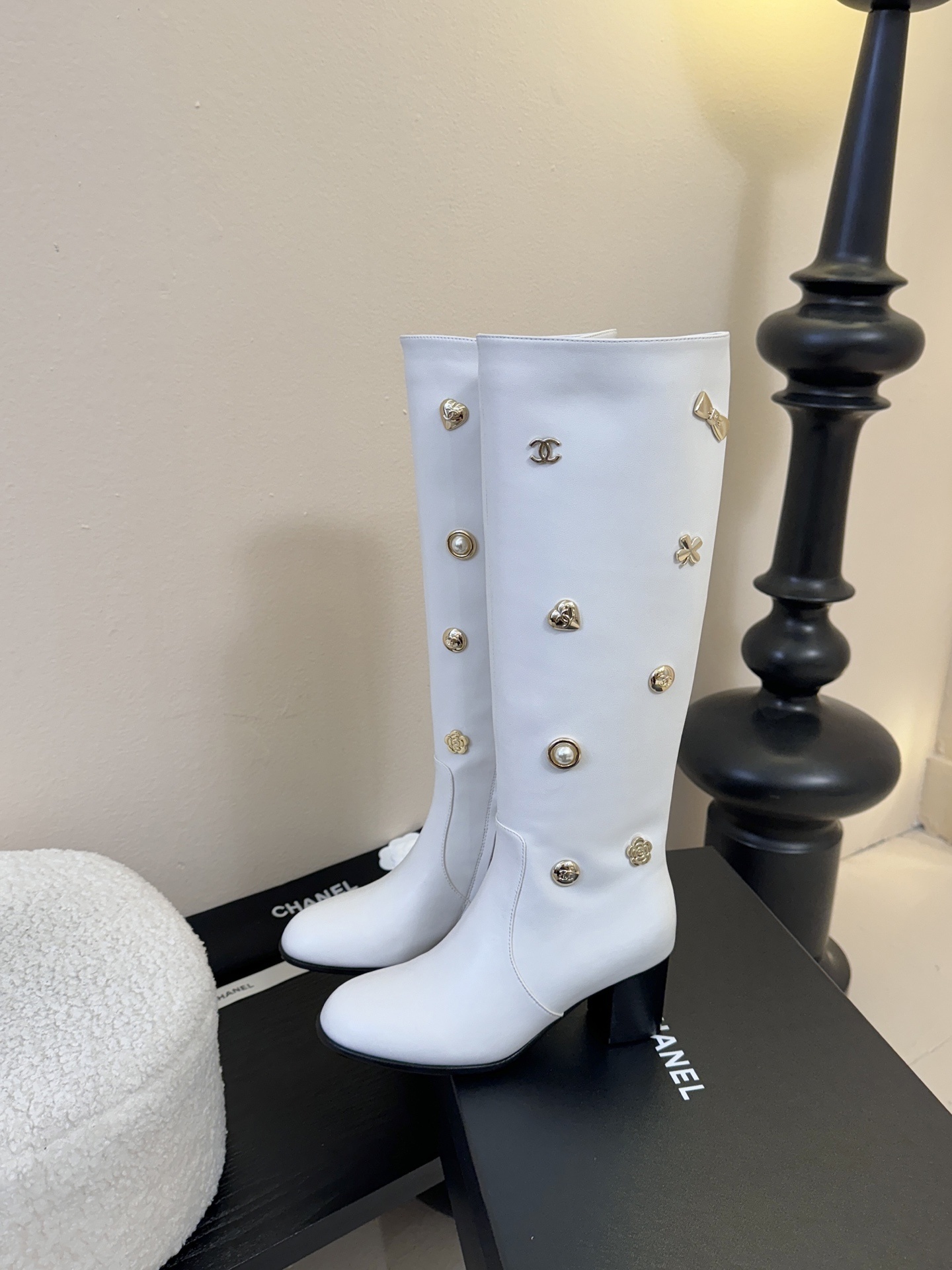 Luxury Chanel white leather knee-high boots decorated with gold-tone CC logos and charms on a display stand. - Hình 5