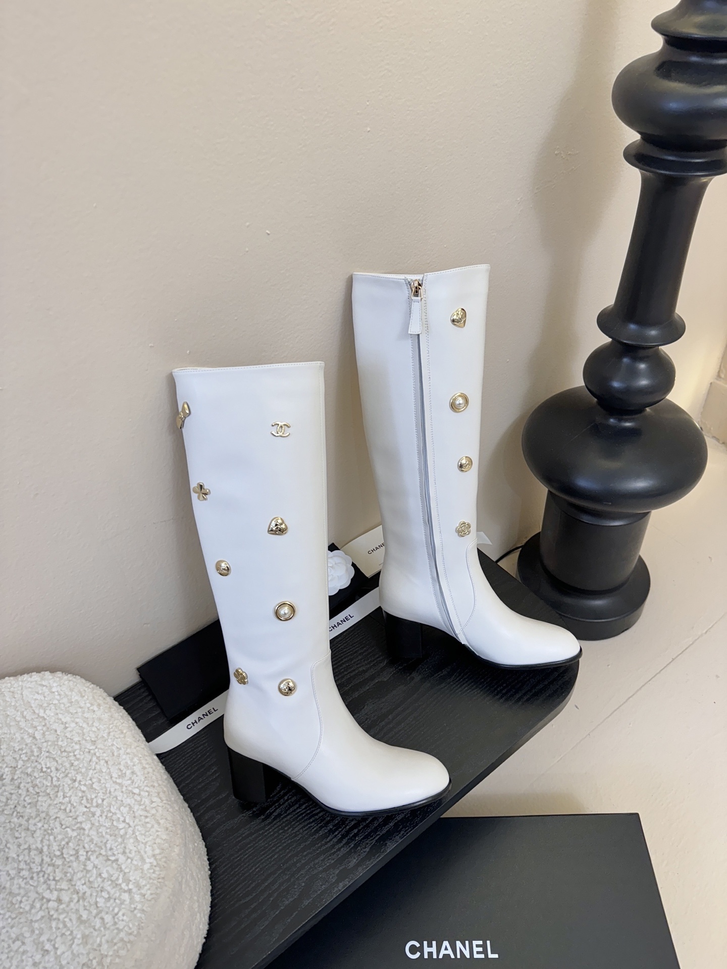 Luxury Chanel white leather knee-high boots decorated with gold-tone CC logos and charms on a display stand. - Hình 4