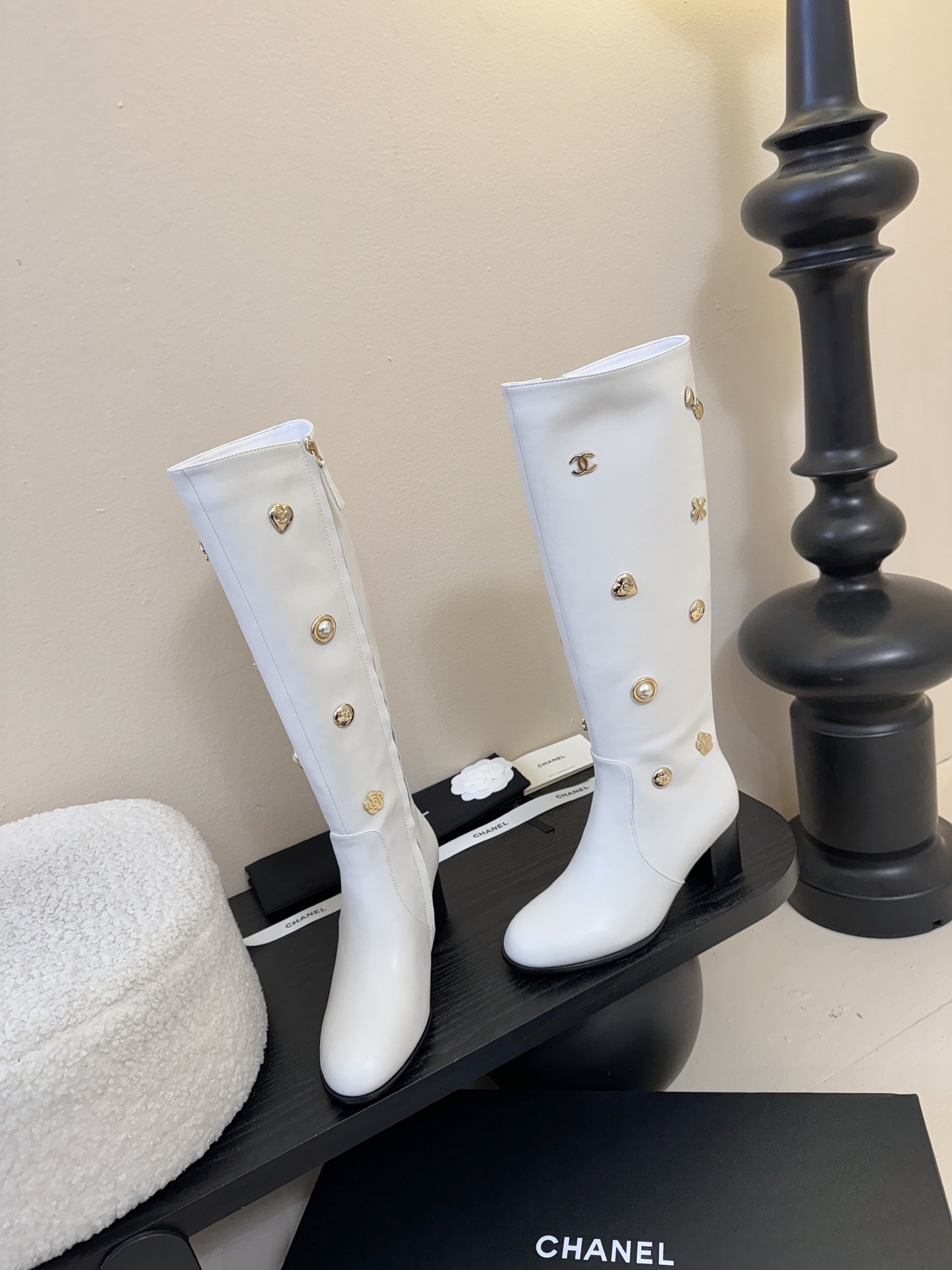 Luxury Chanel white leather knee-high boots decorated with gold-tone CC logos and charms on a display stand. - Hình 3