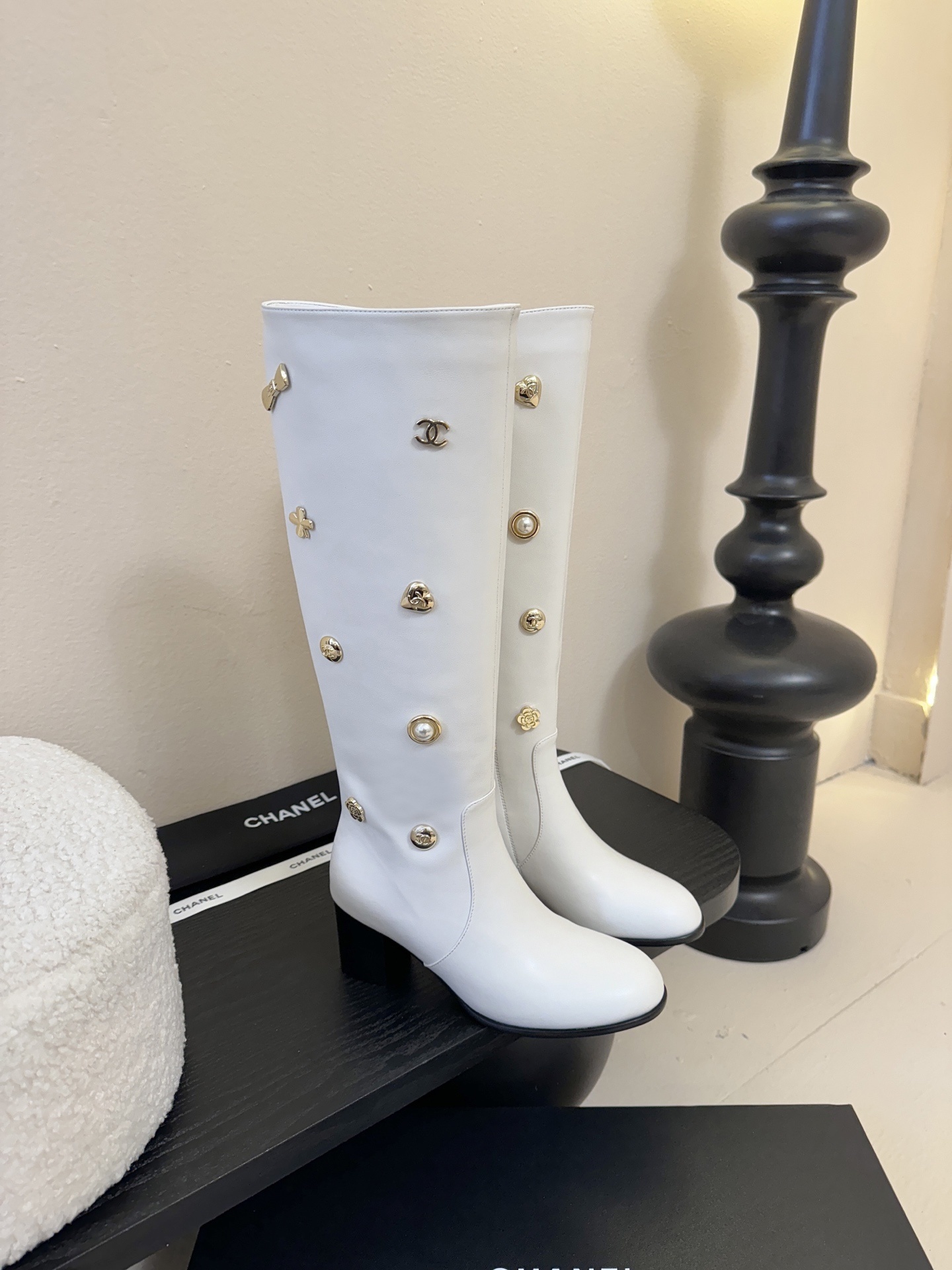 Luxury Chanel white leather knee-high boots decorated with gold-tone CC logos and charms on a display stand. - Hình 2