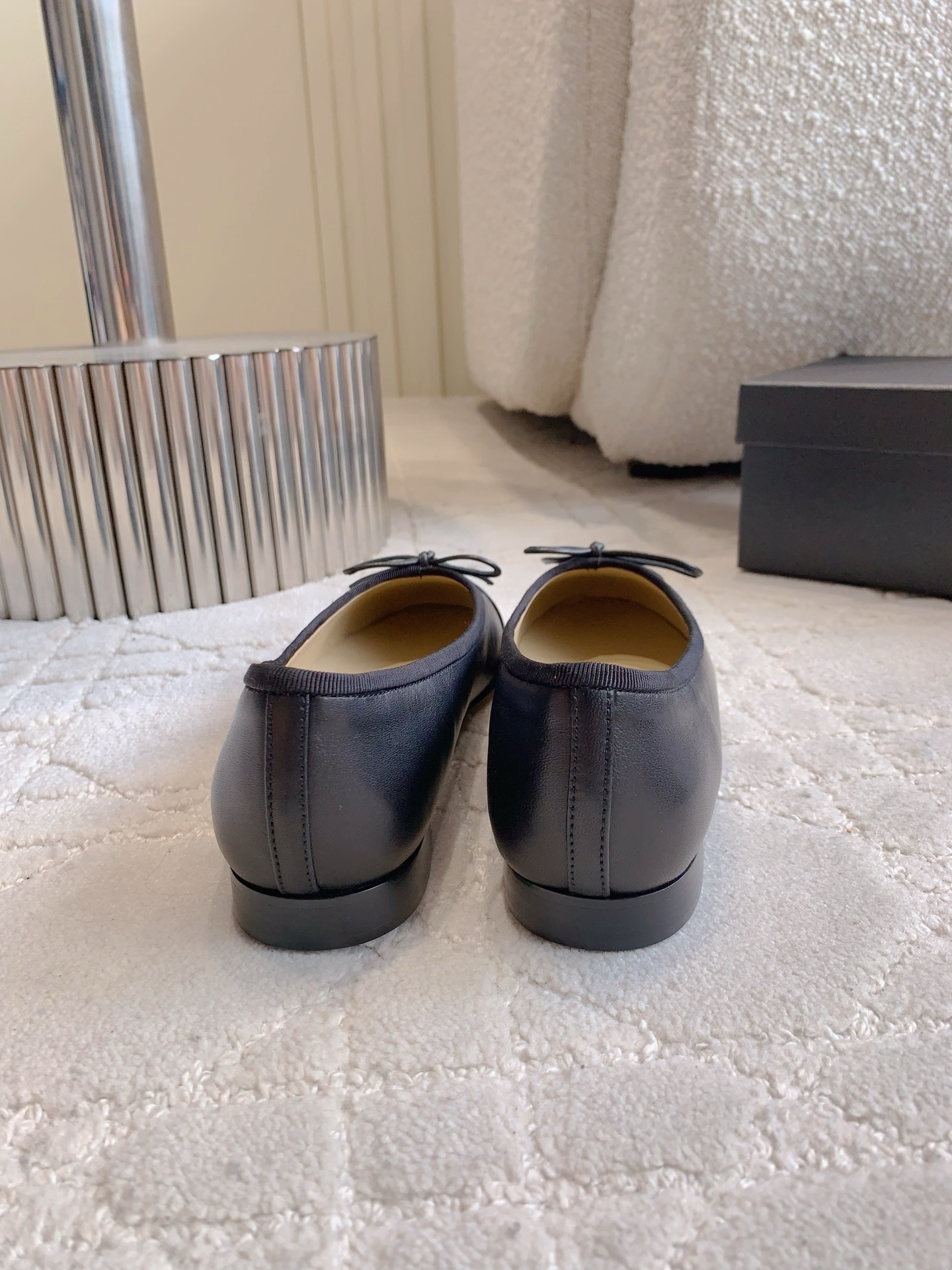 A pair of classic black Chanel lambskin ballerina flats with stitched CC logo and bow detail on a marble surface. - Hình 5