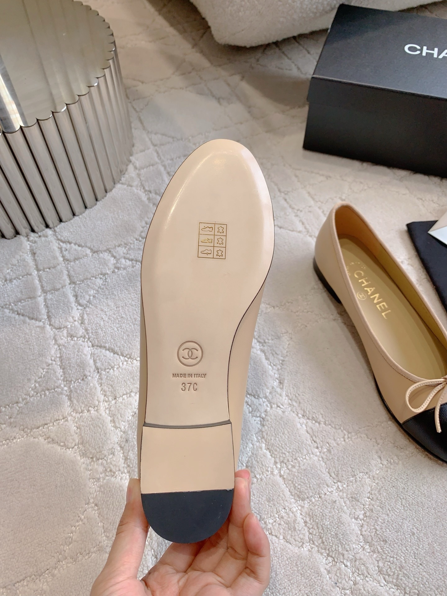 Classic Chanel beige lambskin ballerina flats with black toe caps and bow detail displayed on a marble surface. - Hình 6