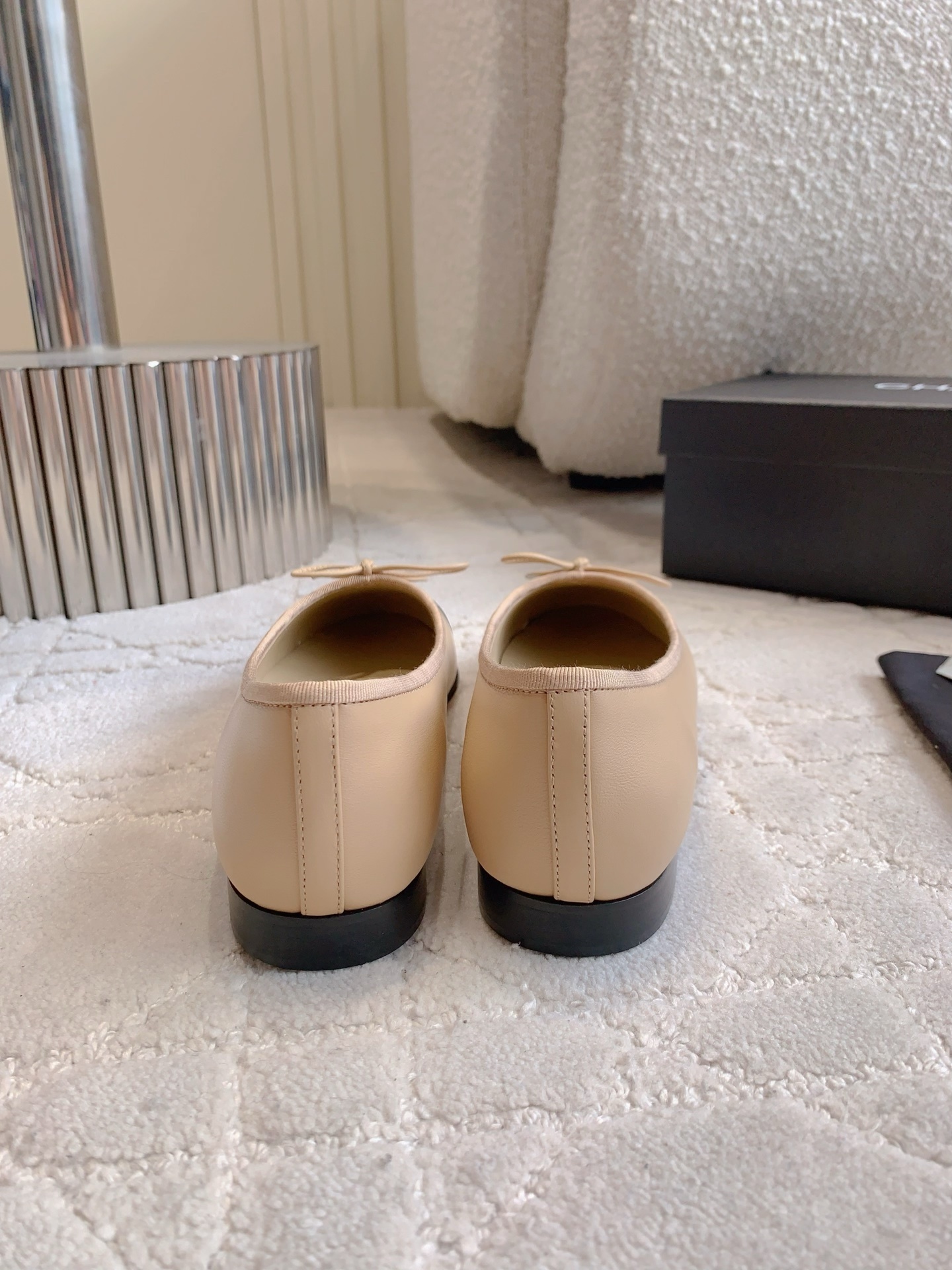Classic Chanel beige lambskin ballerina flats with black toe caps and bow detail displayed on a marble surface. - Hình 5