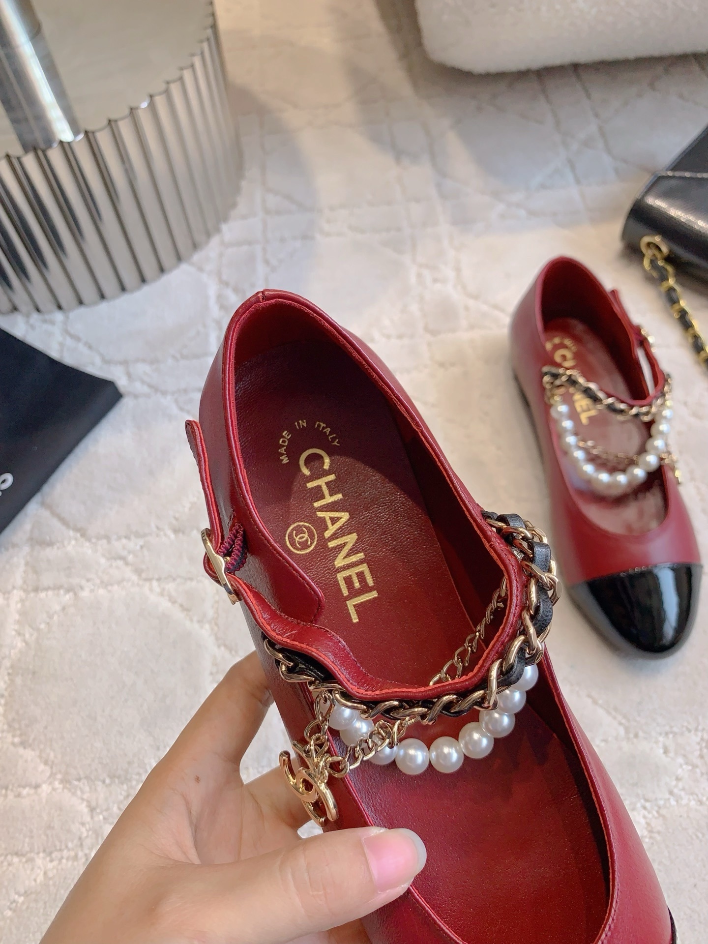 Chanel red leather ballet flats with black patent toe and pearl chain strap on a marble surface. - Hình 8